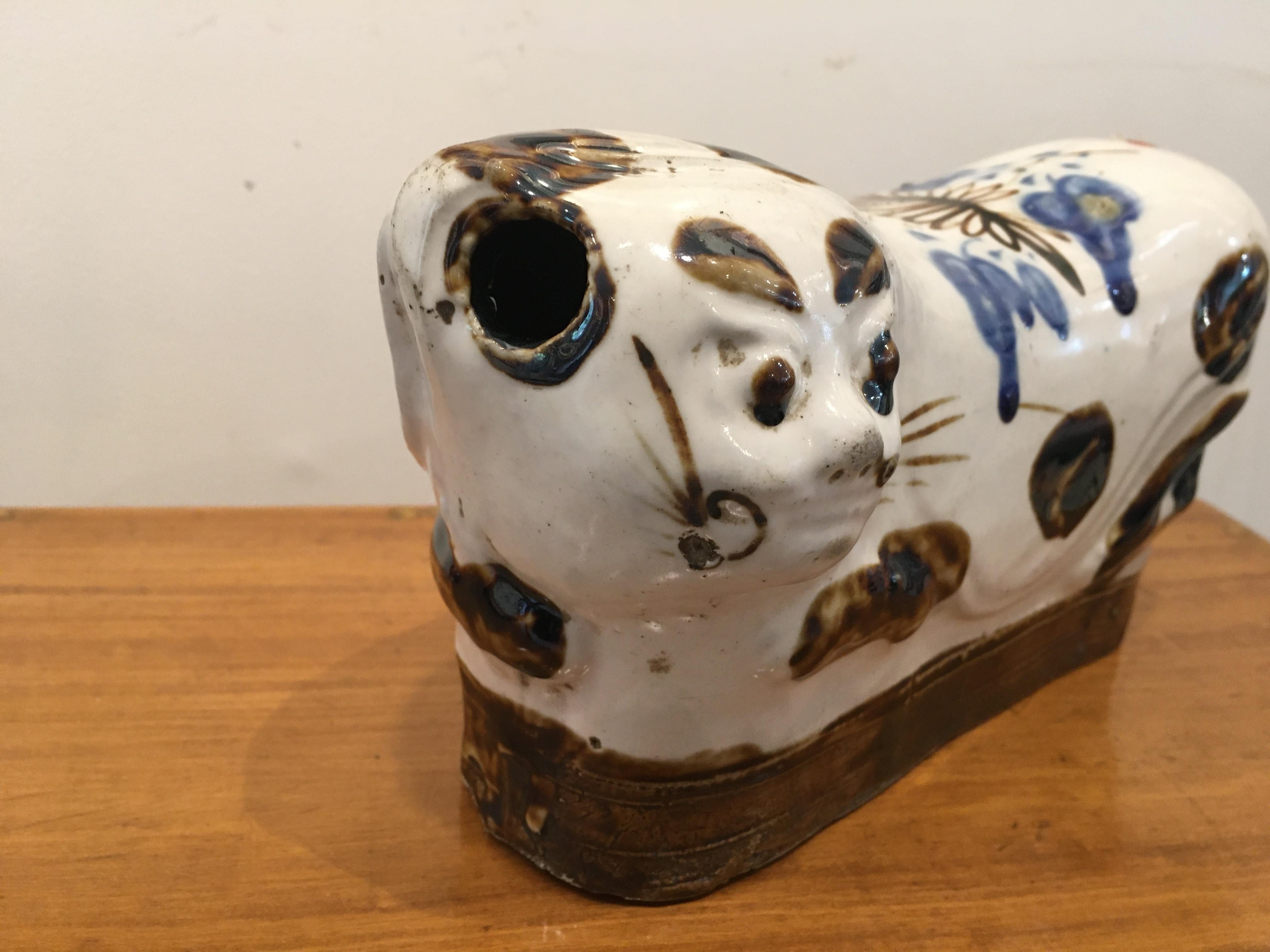 A reclining porcelain cat pillow head rest from the early 1900s, China. These were actually used to keep the spine aligned while sleeping. A production hole at the left side of the head allowed air to escape in order for the piece to maintain its