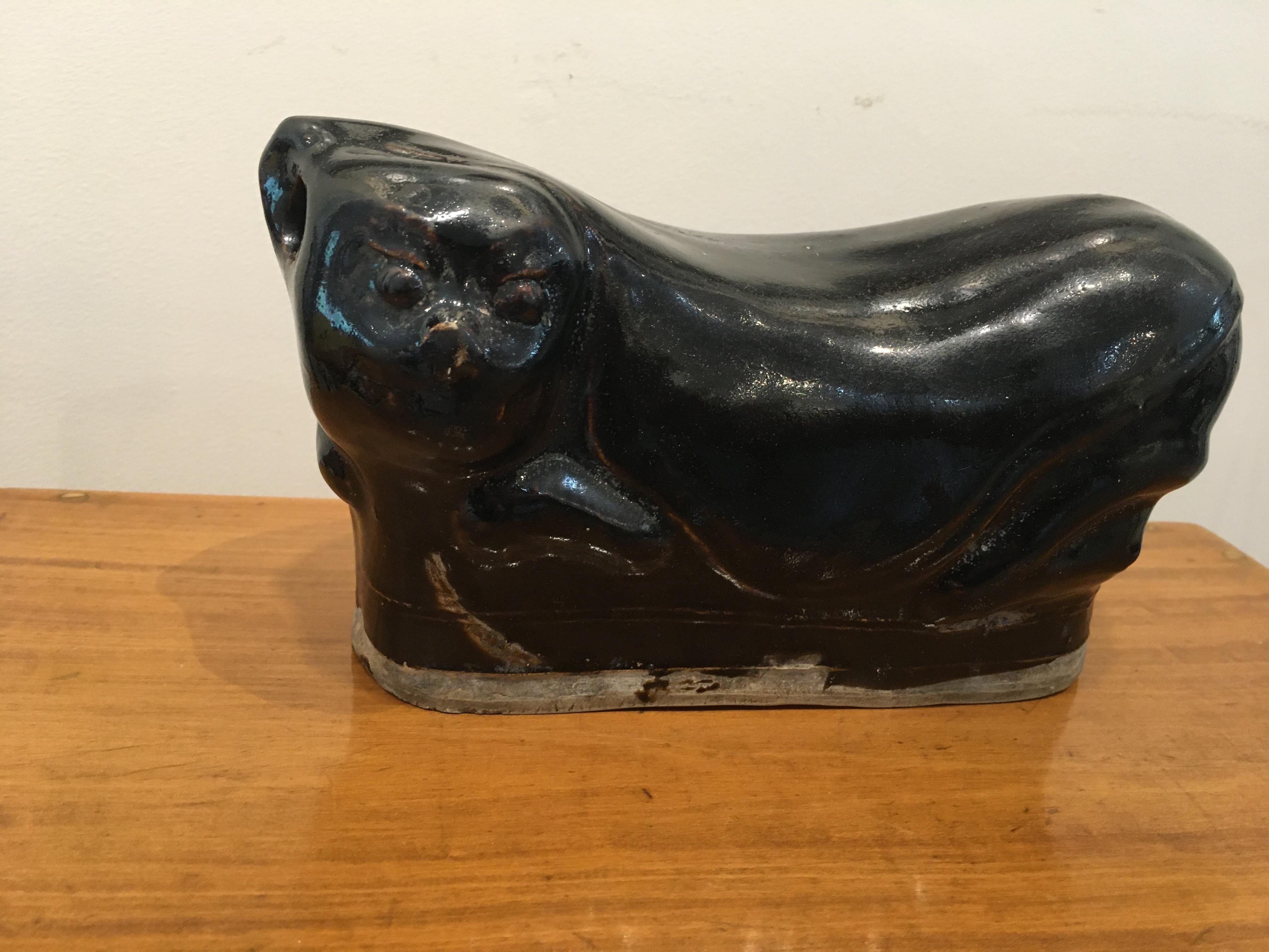 A reclining porcelain cat pillow head rest from the early 1900s, China. These were actually used to keep the spine aligned while sleeping. A production hole at the left side of the head allowed air to escape in order for the piece to keep it's shape