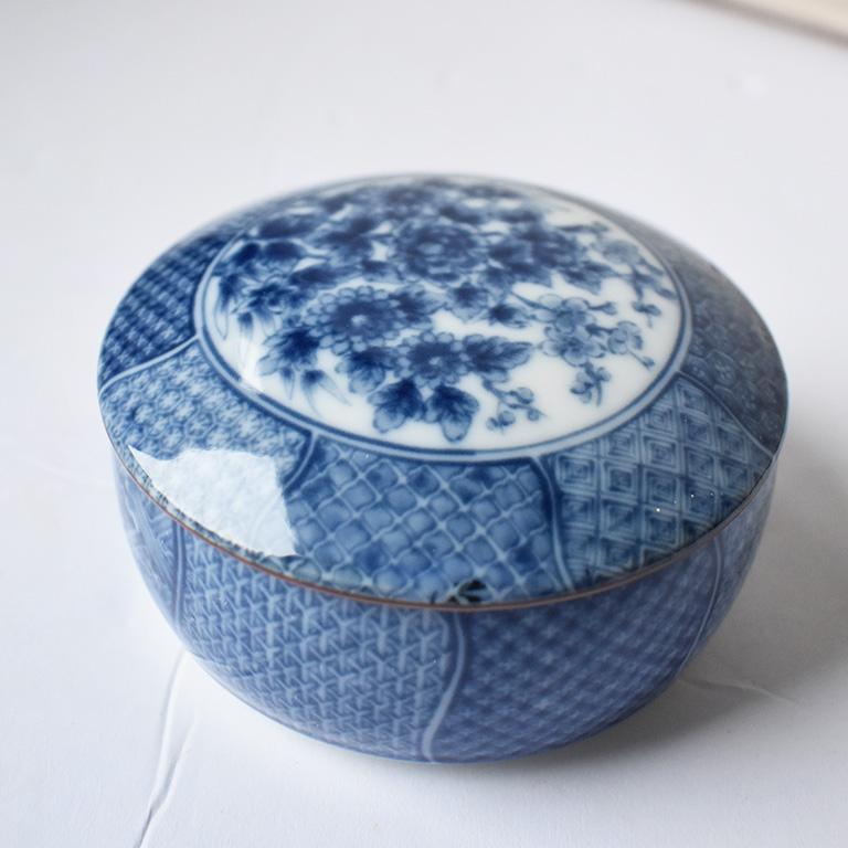Beautiful round porcelain dish or circular box with a cover in blue and white. This circular chinoiserie box with a cover is finely decorated with a crisp blue and white hue. This dish is short and wide with a delicate lid. The top is decorated with
