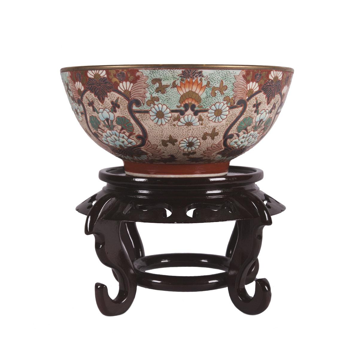 This Imari style bowl from China is hand painted and made of porcelain. This bowl includes the wooden stand shown in the photos. The bowl measures 10 inches in height and is 10 inches in diameter. The bowl is 10 inches in depth. 