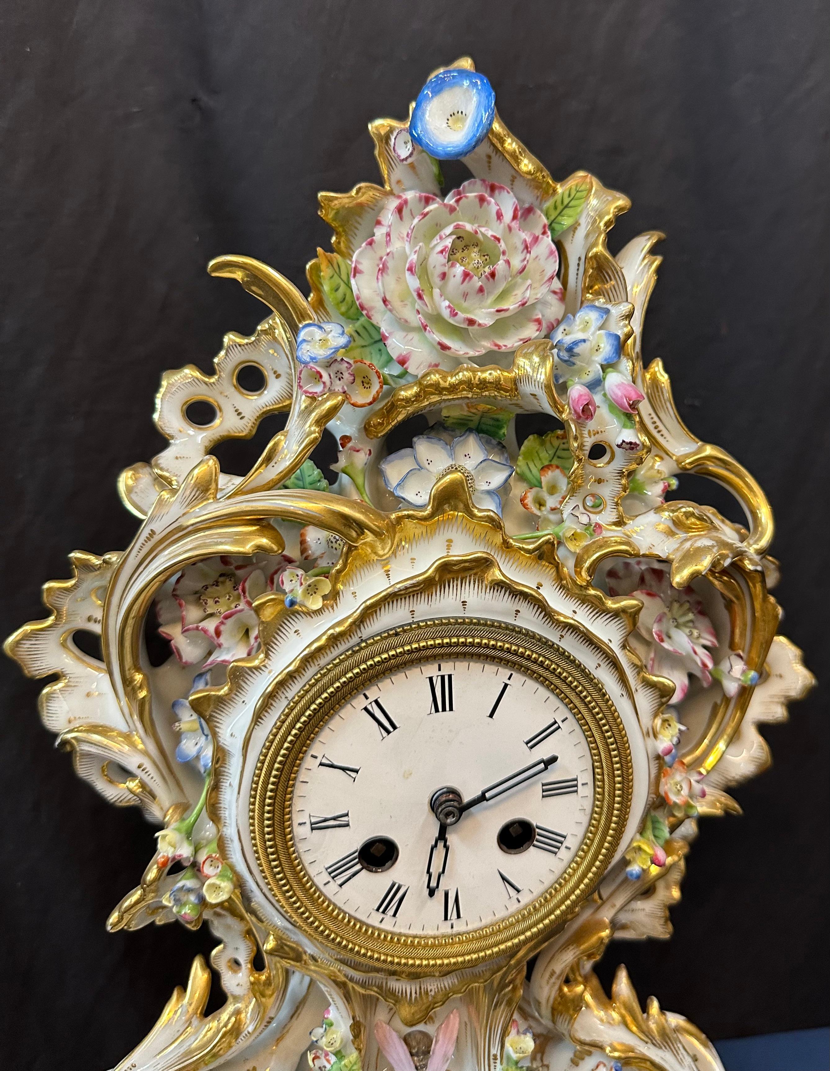 This vintage elaborately decorated French porcelain mantle clock dates from the 1850's. The delicate porcelain has hand painted colorful sculpted flowers, gleaming gold gilt scrolls & painted floral accents that comprise the body of this rare