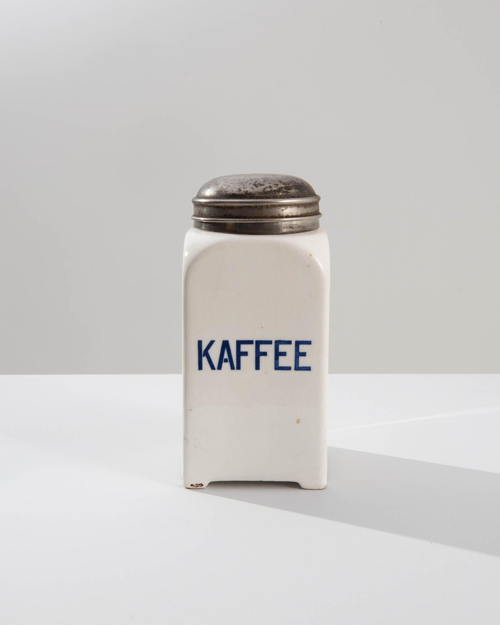 A vintage porcelain jar from 20th Century Germany, originally used for storing coffee. The slick white glaze is bright and inviting, attractive blue letters advertise the contents, ‘KAFFEE.’ Subtly ornamented the metal lids feature raised ridges,