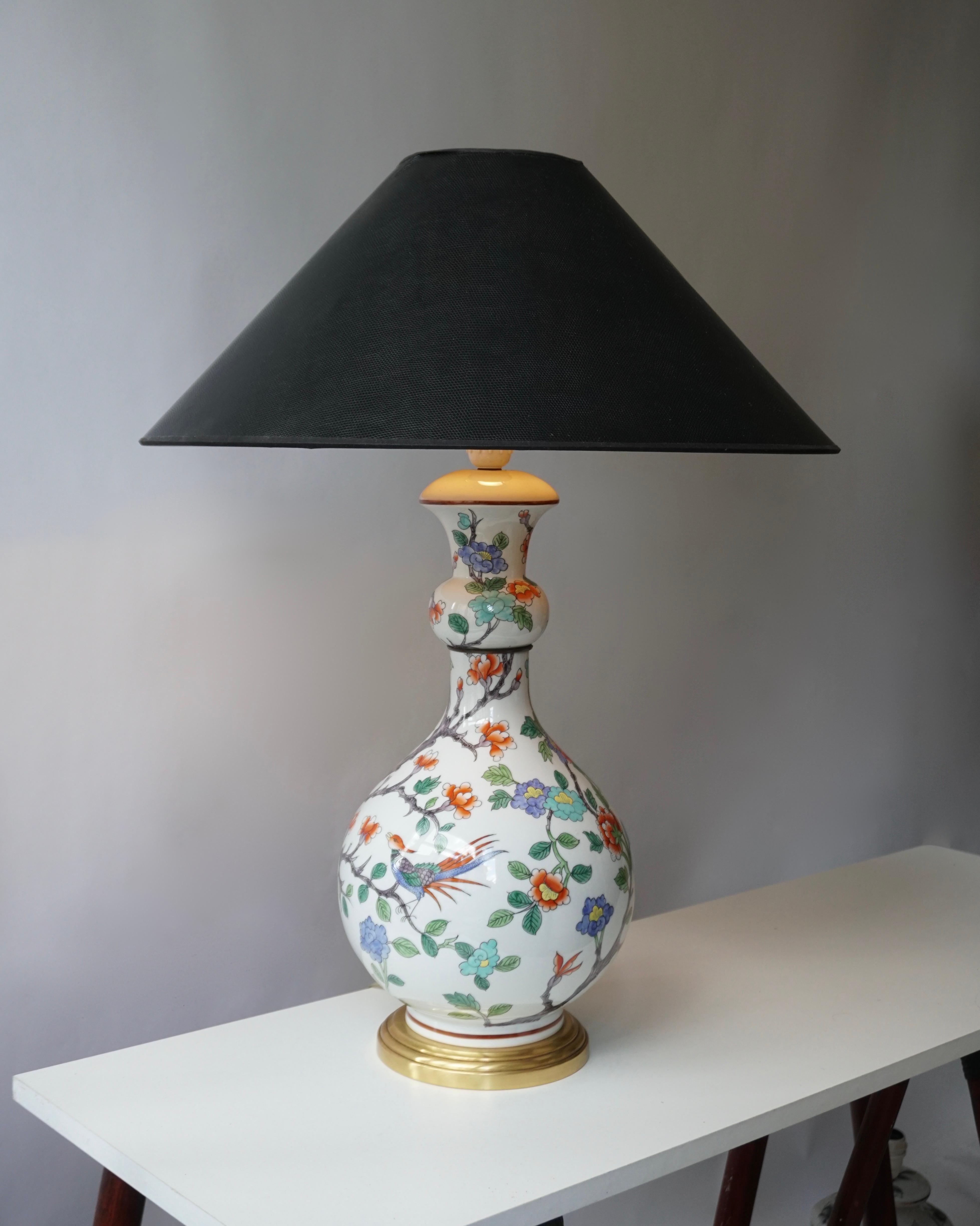Lampe de table en porcelaine décorée de fleurs colorées et d'un oiseau.
Le dessous porte le cachet bleu sous glaçure 