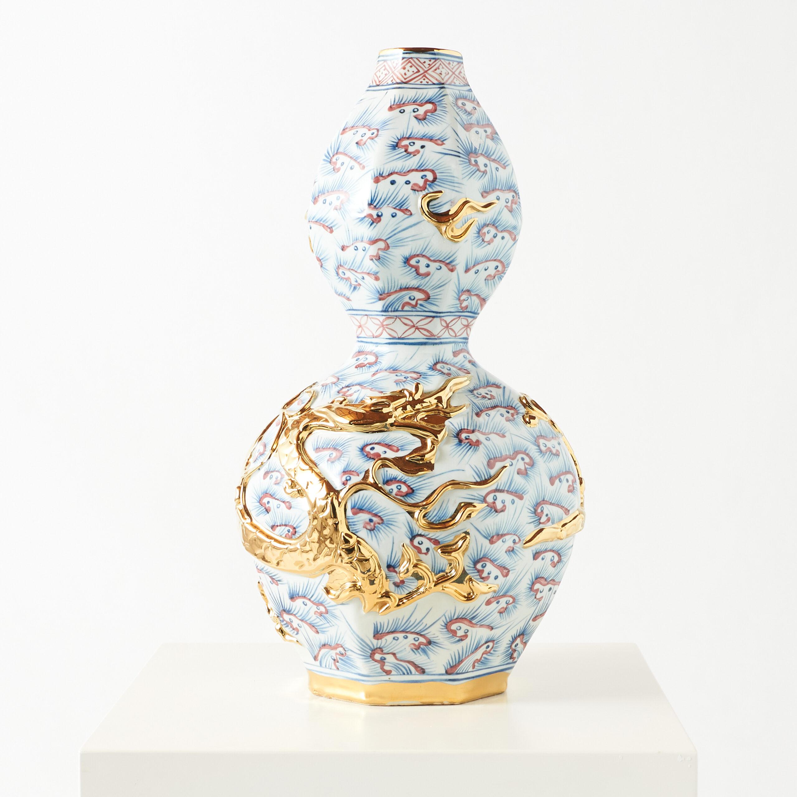 Doppelkürbis-Vase aus Porzellan mit goldenem Drachen

Diese chinesische Porzellanvase zeigt einen goldenen Drachen, der sich um die untere Birne windet und Macht und Glück symbolisiert. Sie ist mit blauen und roten stilisierten Wolken verziert, die