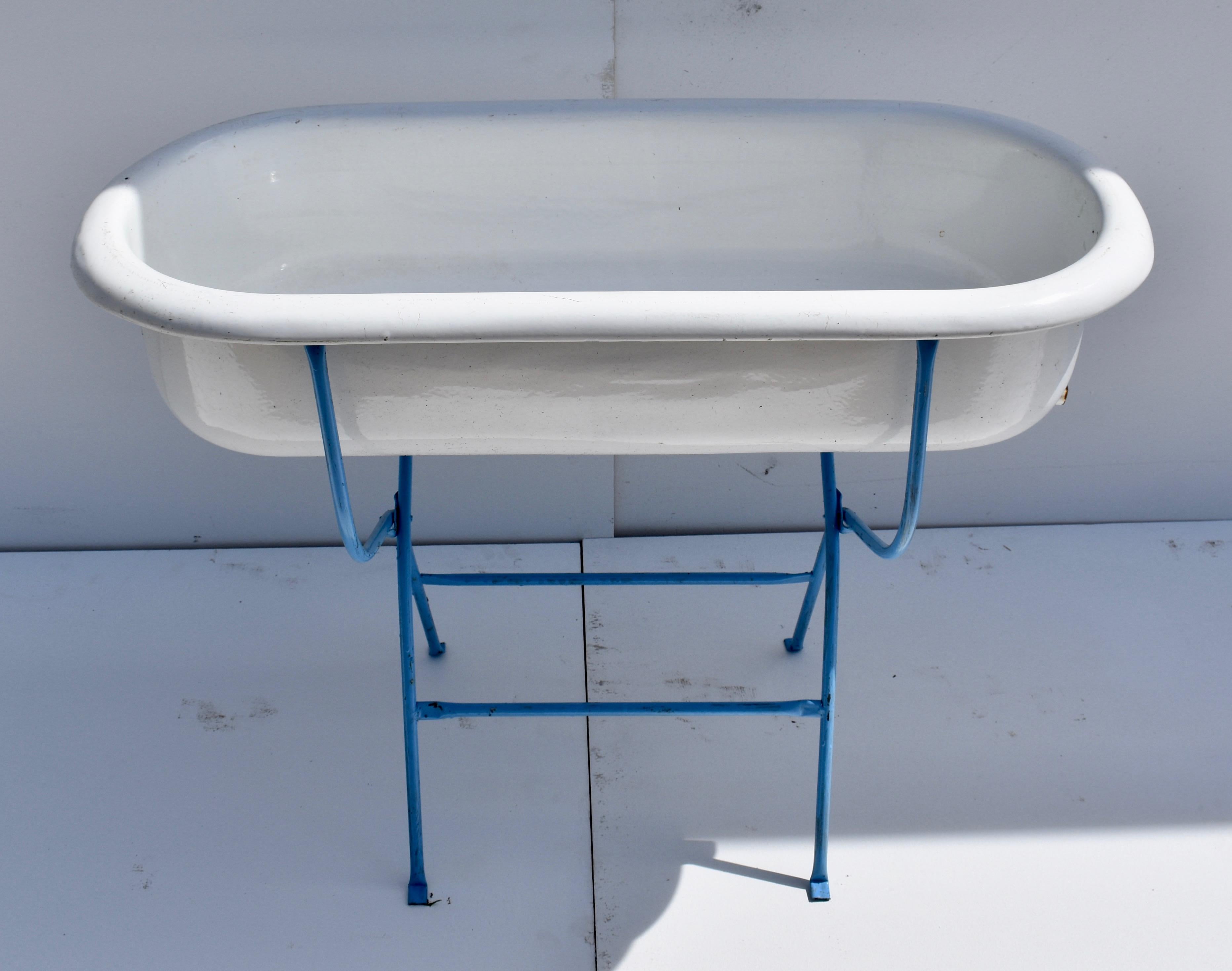This is a charming porcelain enameled baby bath by Lampart of Hungary, mounted on an original folding wrought iron stand, recently re-painted in blue. With fine fall weather approaching, it would be great filled with bottles of beer or wine on ice,