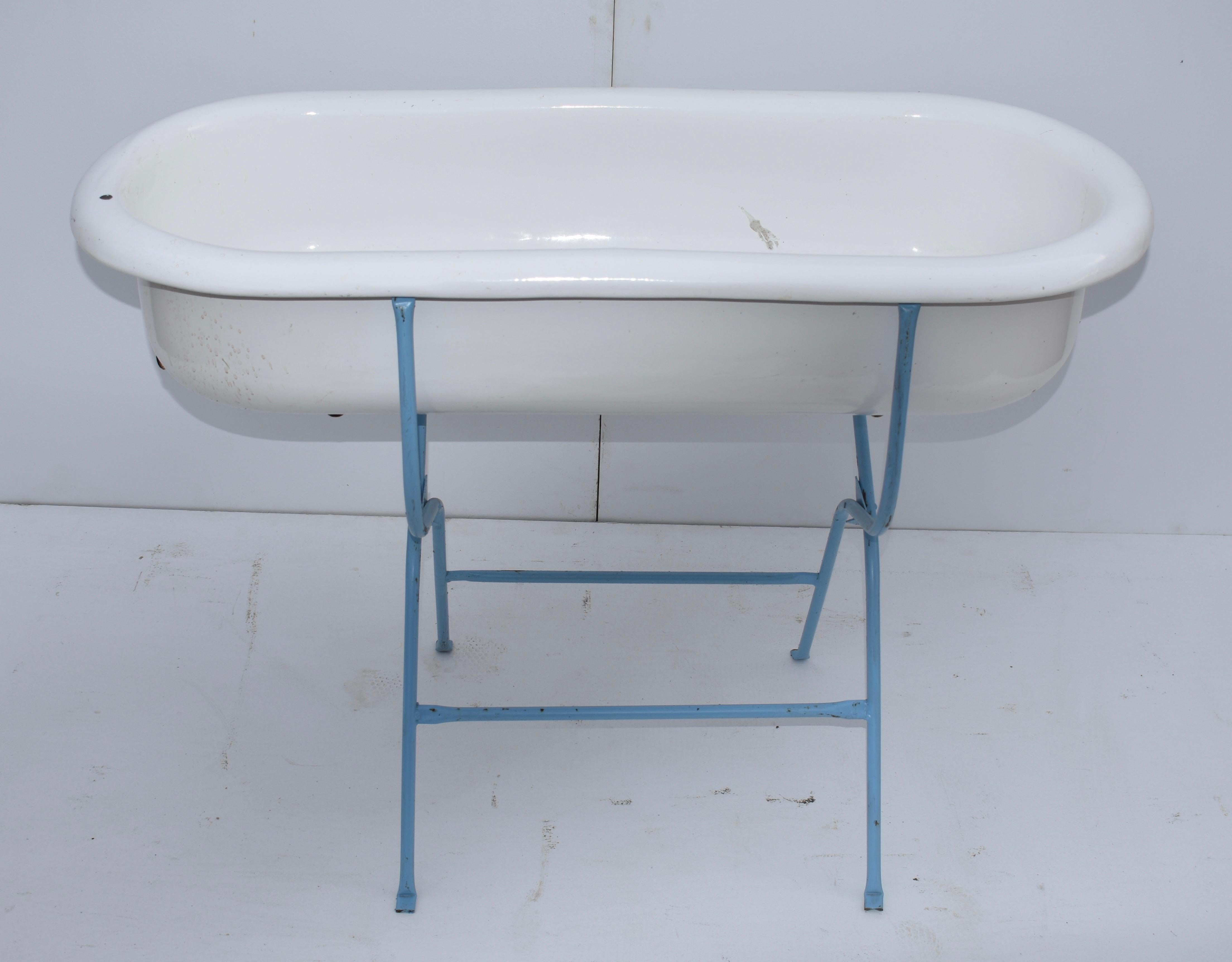 This is a charming porcelain enameled baby bath by Lampart of Hungary, mounted on an original folding wrought iron stand, recently re-painted in blue. Spring will be here before you know it and this would be great filled with bottles of beer or wine