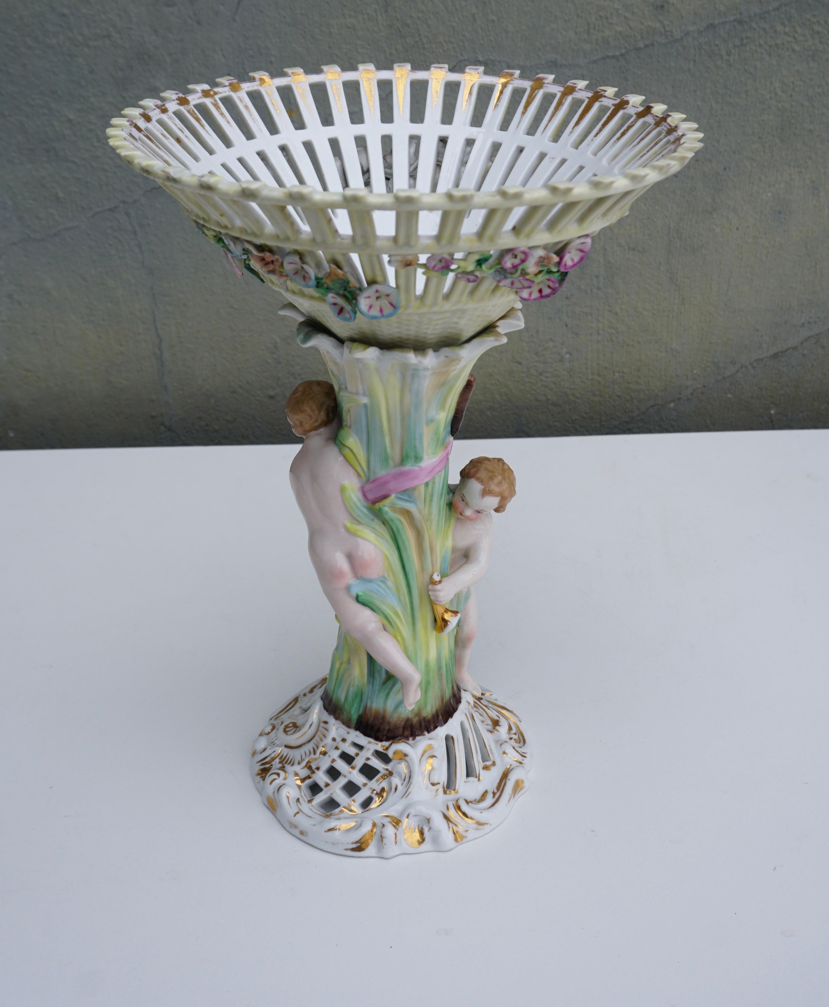 Cet objet est une jardinière en porcelaine du 19e siècle, magnifiquement émaillée de riches couleurs avec des gerbes de fleurs et des reflets dorés. Cette superbe pièce rococo présente également une fleur de rose en relief, des feuilles et des