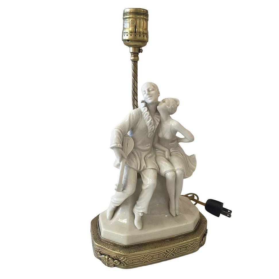 Lámpara figurita de porcelana y latón de la época Art Decó de una chica Arlequín besando a su payaso juglar.

Medida: Base 7