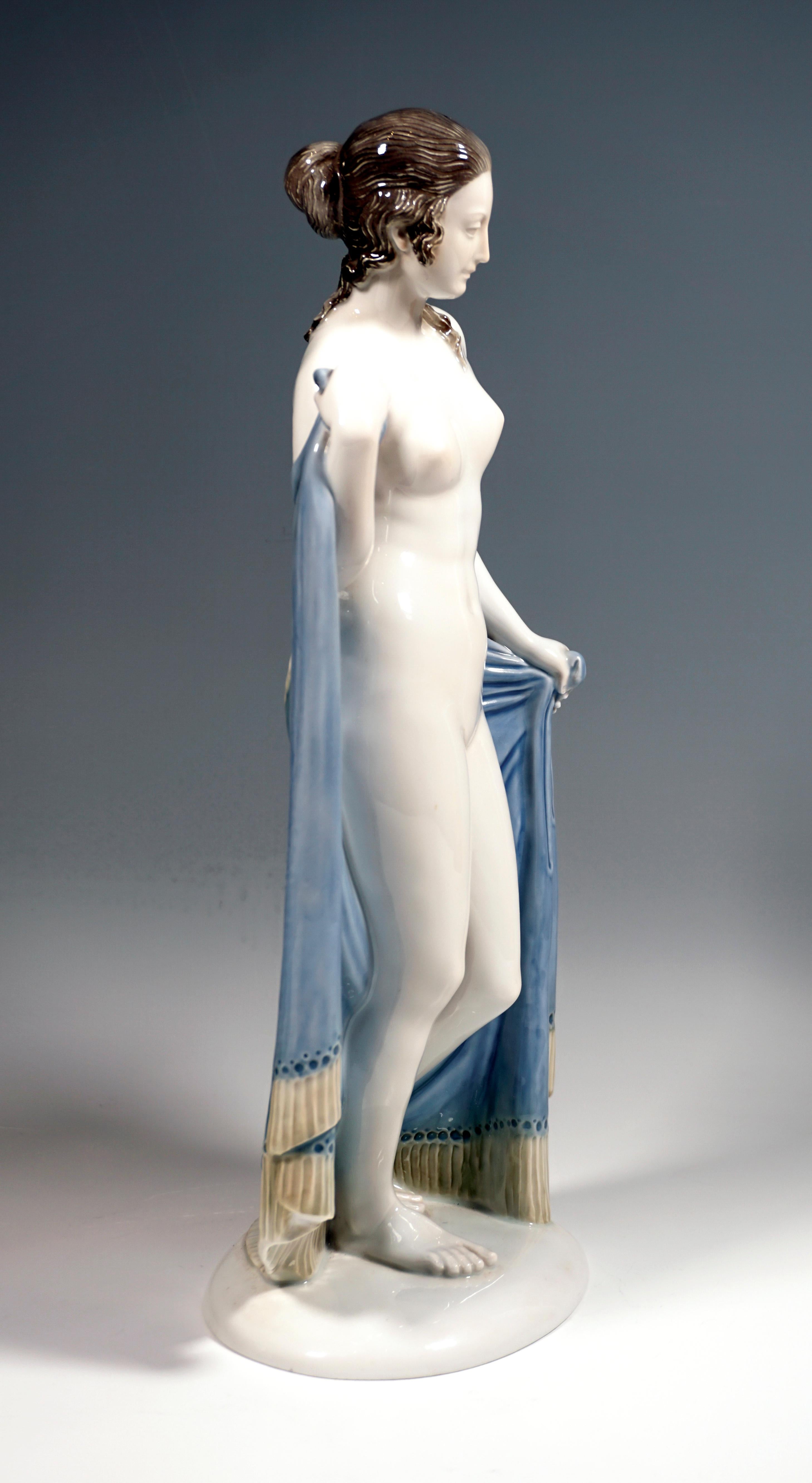 Large and rare Art Deco porcelain figurine of the 1920s.
Naked young lady with a well-formed, slender figure and hair combed back and pinned up in contraposto, holding a large, light blue cloth with cream-colored fringes behind her with both hands