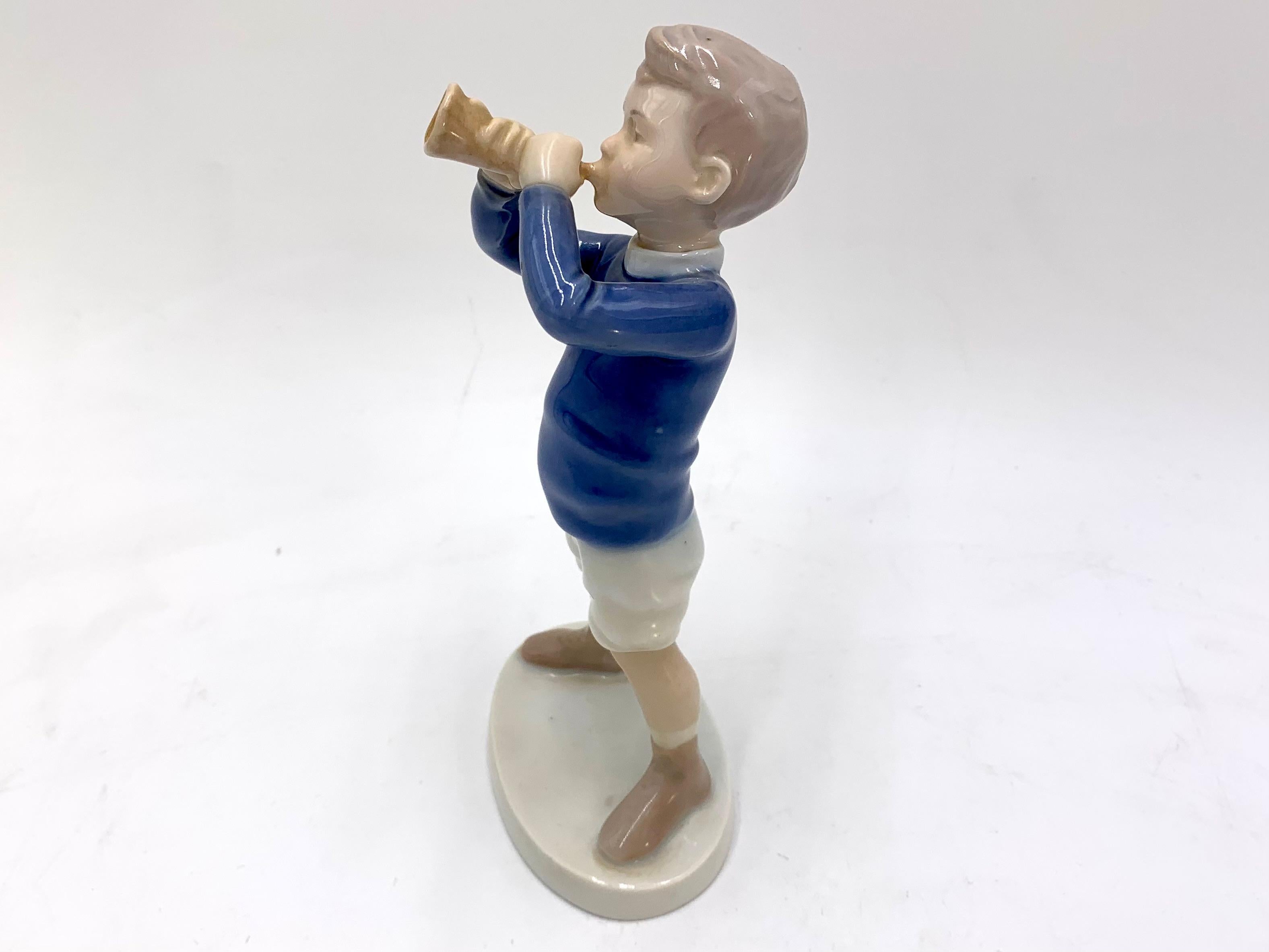 Porzellanfigur eines Jungen mit einer Trompete

Hergestellt in Dänemark von Bing & Grondahl

Produziert in den Jahren 1970-1983.

Modellnummer # 1792

Sehr guter Zustand, keine Schäden

Maße: Höhe 19cm Breite 8,5cm Tiefe 6cm.