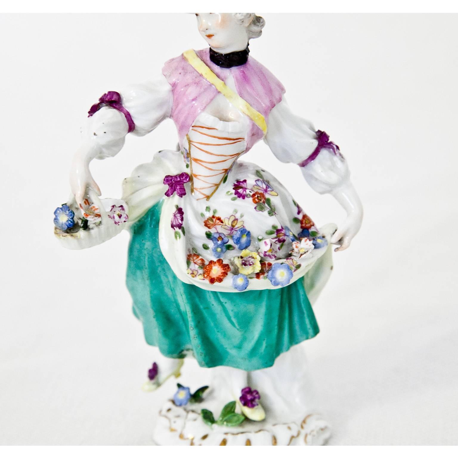 Porcelain figurine of a girl in elegant clothing with flowers by J. J. Kaendler. Blue swords mark towards the base.