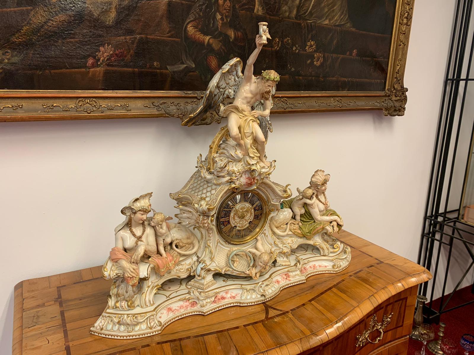 A Berlin (K.P.M) Porcelain figural mantel (fireplace) clock.
Dated 1892 blue Scepter and Iron-red orb marks, impressed model.

In the Neo Rococo style, modeled as father time holding a winged hourglass aloft,
seated on a spoked wheel among the