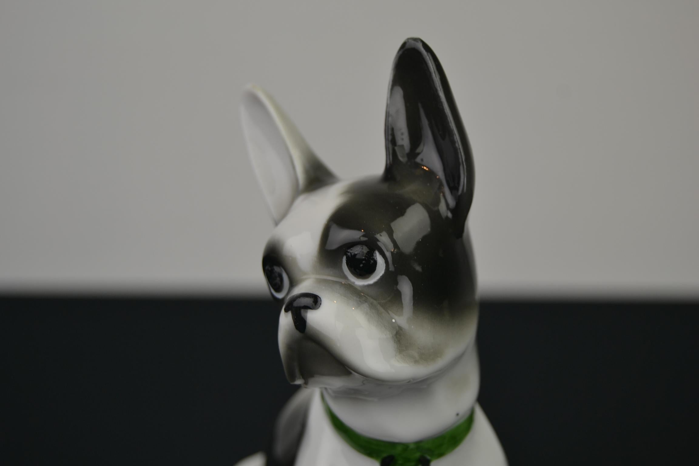 French bulldog sculpture or Boston terrier sculpture of porcelain.
It's a white with dark grey bulldog wearing a green collar.
A dog sculpture to add to your collection. 
He does not have chips, but does have some small fabric imperfections (