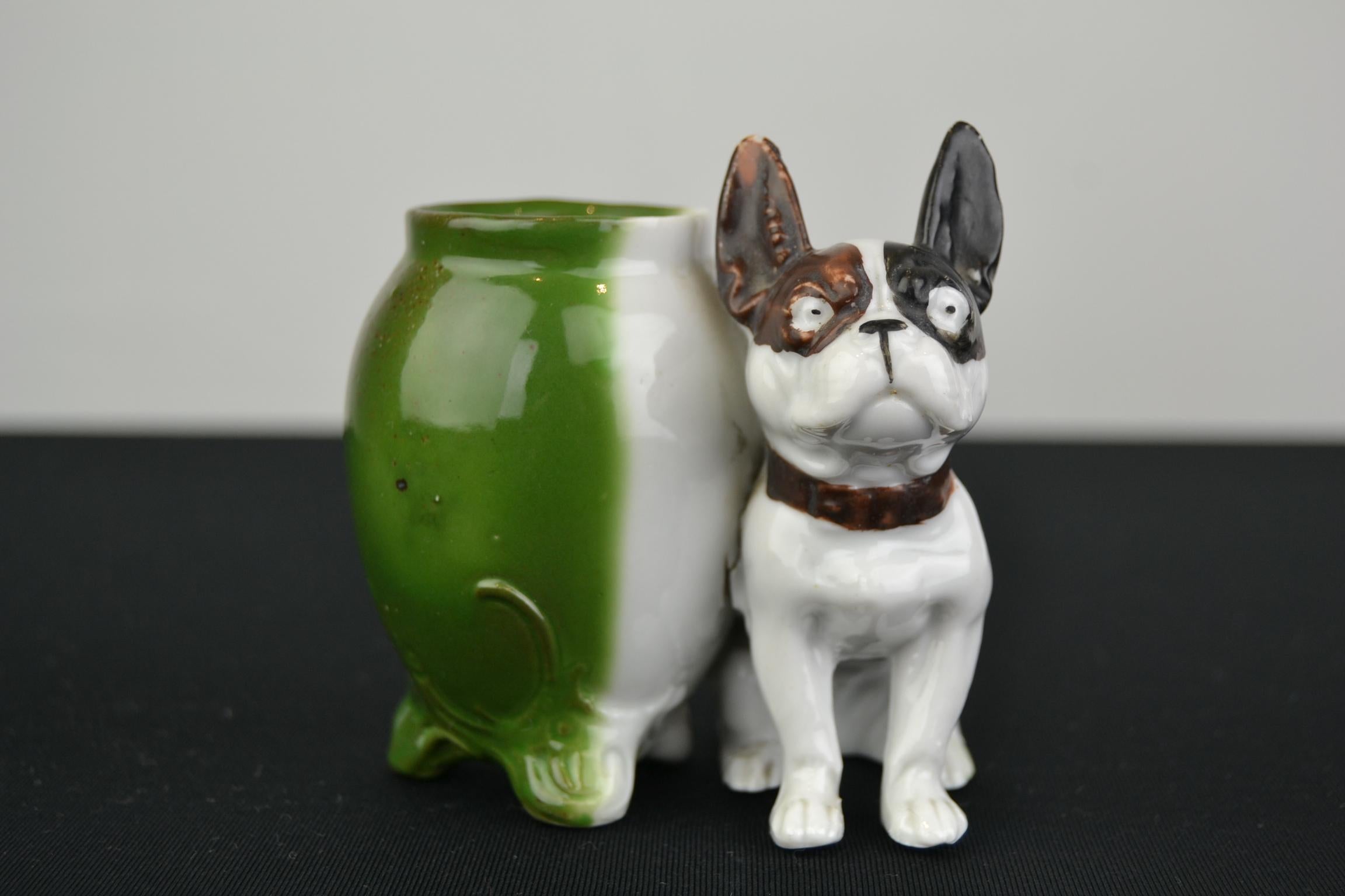 French bulldog sculpture with mustard pot. This porcelain dog sculpture dates from the Art Deco period, circa 1930s-1940s. This white Bulldog Figurine has a brown and black ear and a green mustard pot or storage pot. This Bully is in good vintage