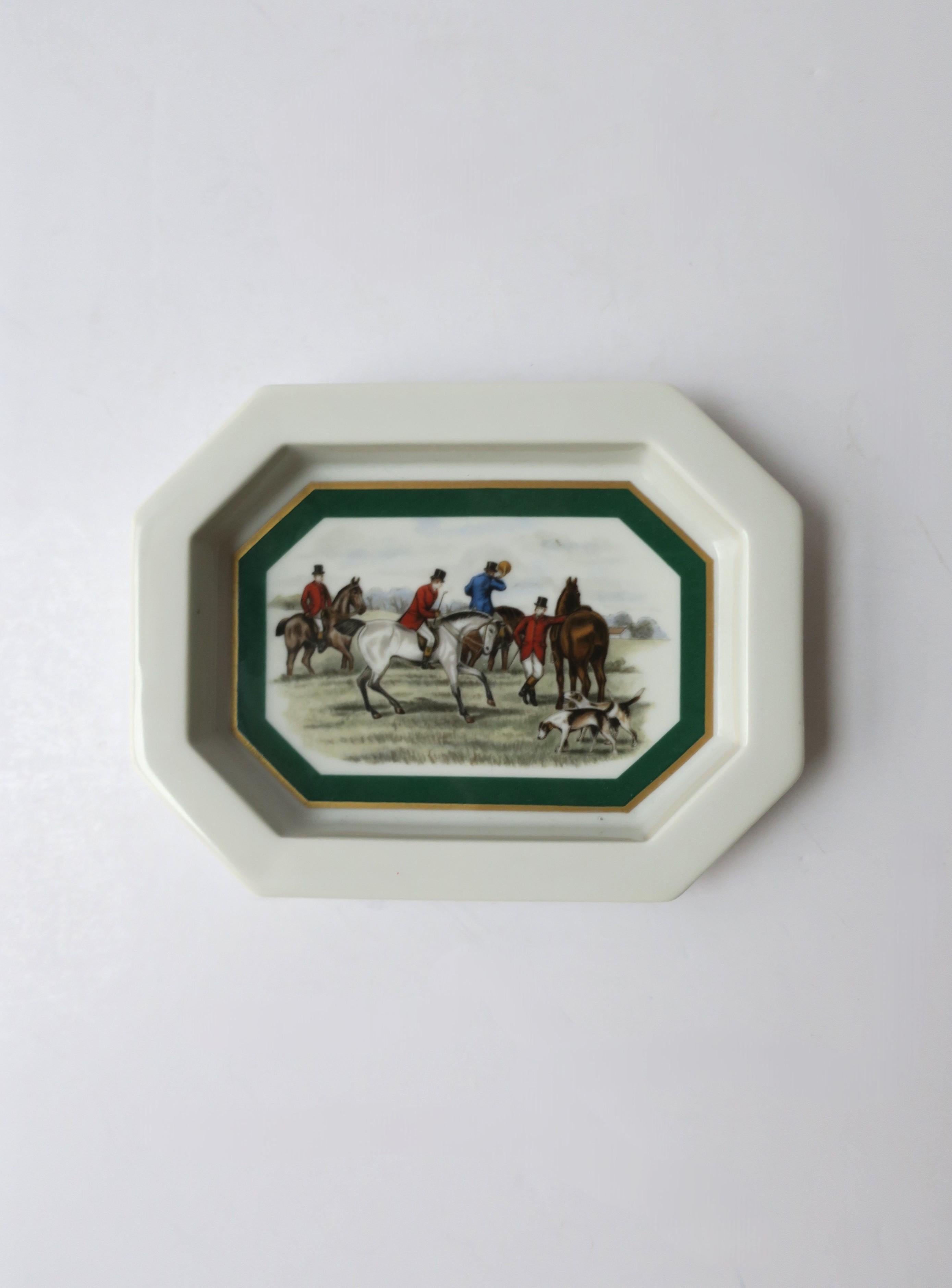 Plat à bijoux en porcelaine avec scène équestre, vers le milieu du 20e siècle, Europe. Un plat à bijoux/petit vide-poche octogonal avec des détails en or et en vert émeraude encadrant une scène de cavaliers, de chevaux et de chiens de chasse. Dans