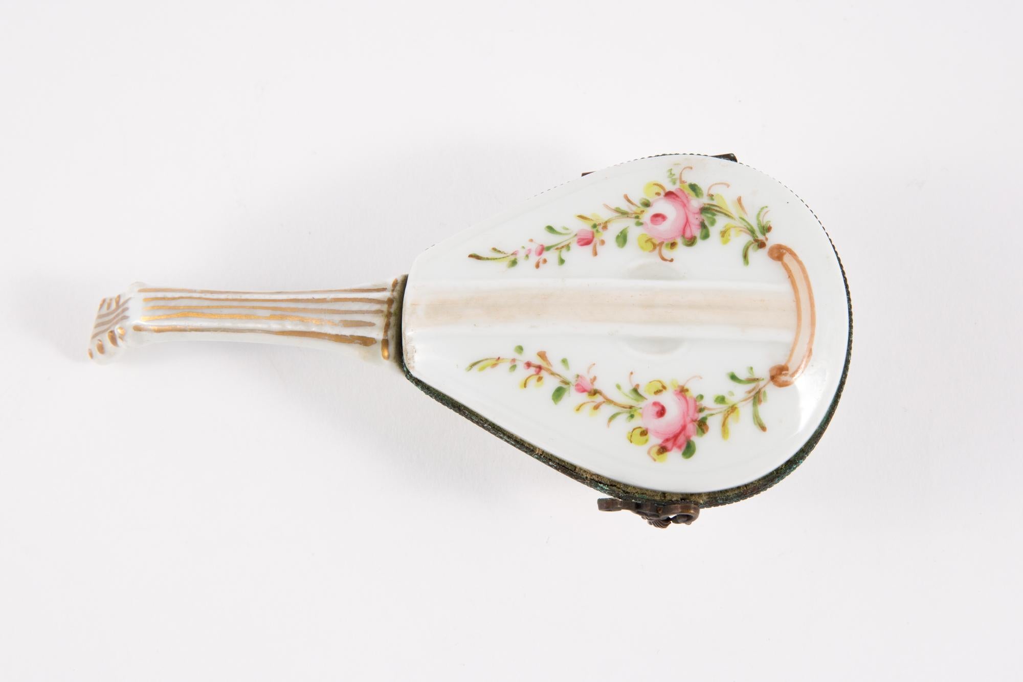 Porcelain mandolin pill box featuring a metal frame a crown clasp and a polychrome floral decor.
In excellent vintage condition. Made in France. 
Height 1.5in. (4cm)
Length 5.5in. (14cm)
Width 2.3in. (6cm)
We guarantee you will receive this gorgeous