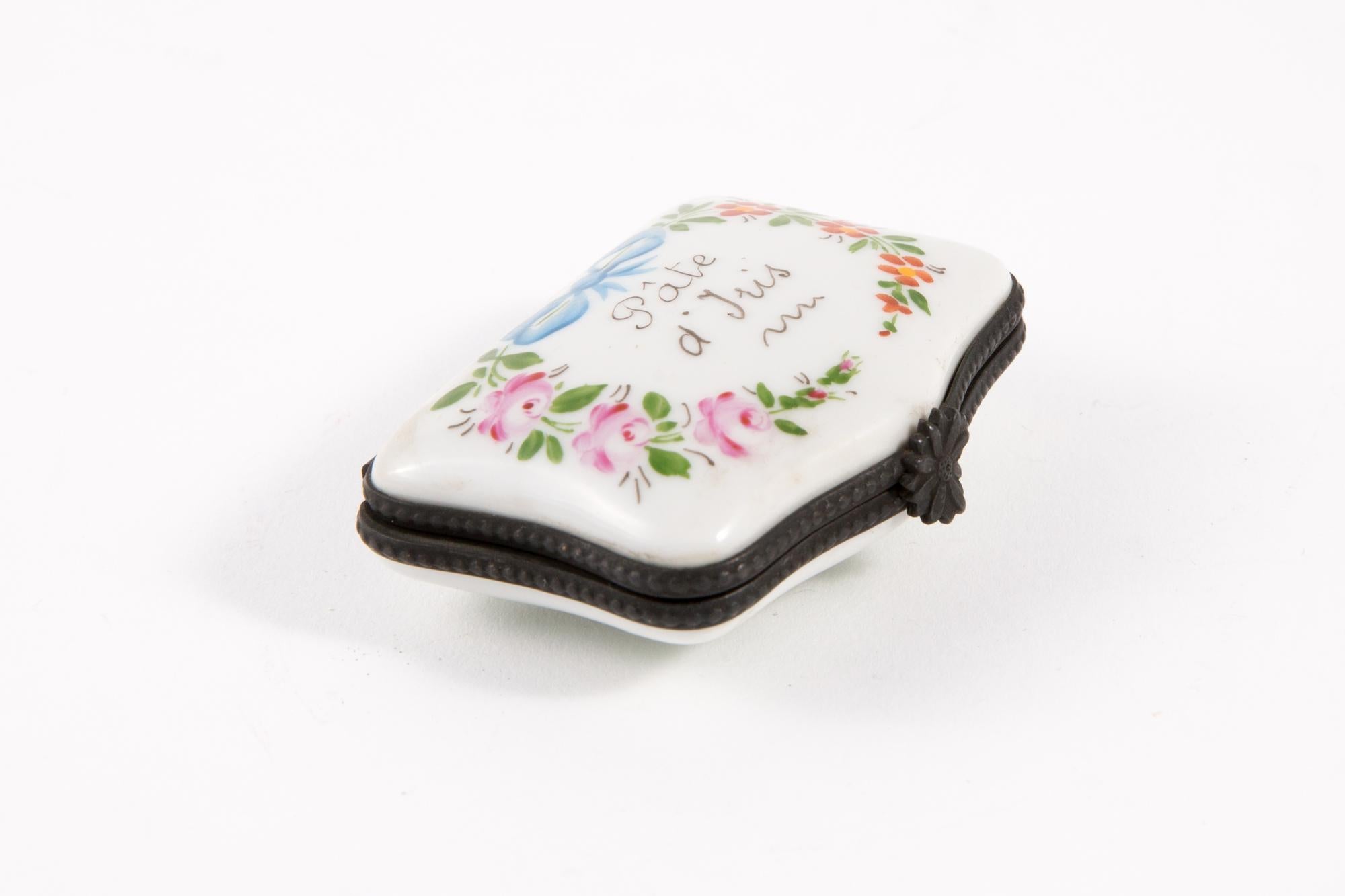 Porcelain Pâte d' Iris (soft extract) polychrome pill box featuring a metal frame, a flower claps, leaves painted inside and a polychrome floral decor and text. 
Hand Painted
In good vintage condition. 
Width 1.9in. (5cm)
Length 2.3in. (6cm)
Heigth: