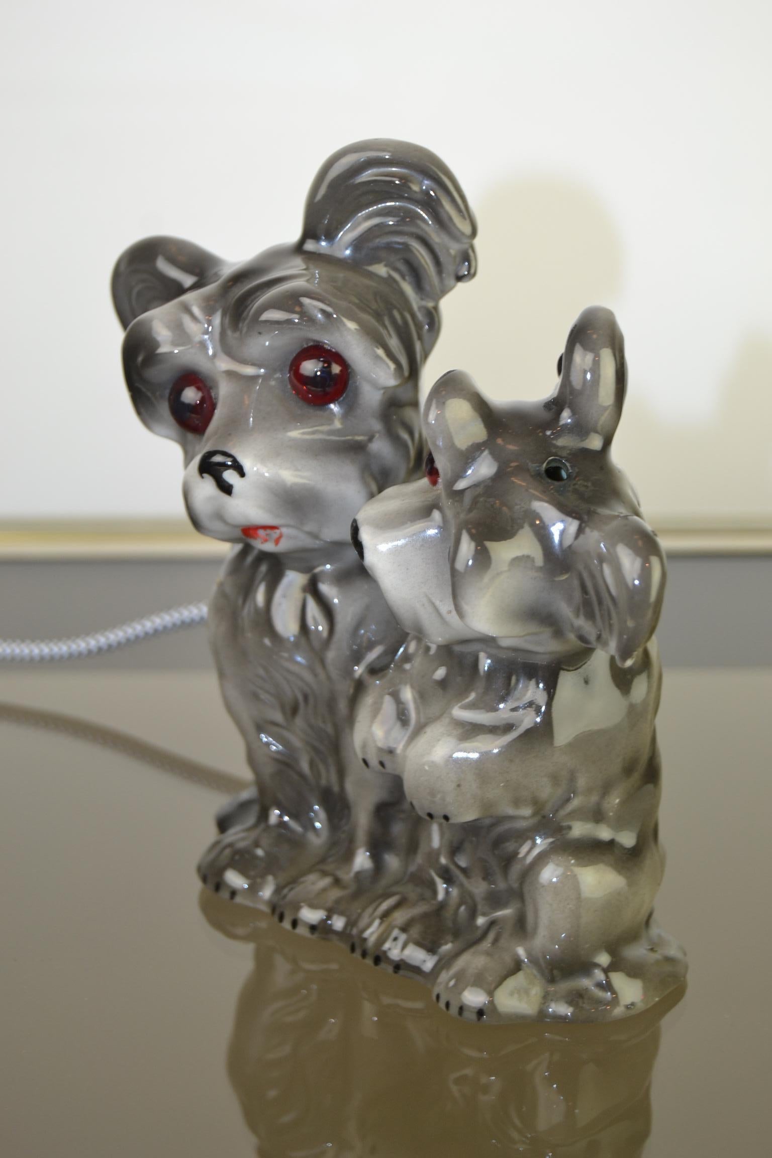 Niedliche Tischlampe - Parfümlampe - Beistelllampe mit 2 Hunden.
Diese Parfümlampe aus Porzellan besteht aus einem Hundepaar, 
stammt aus den 1950er Jahren. 
Hat eine neue Verkabelung. 

    
 