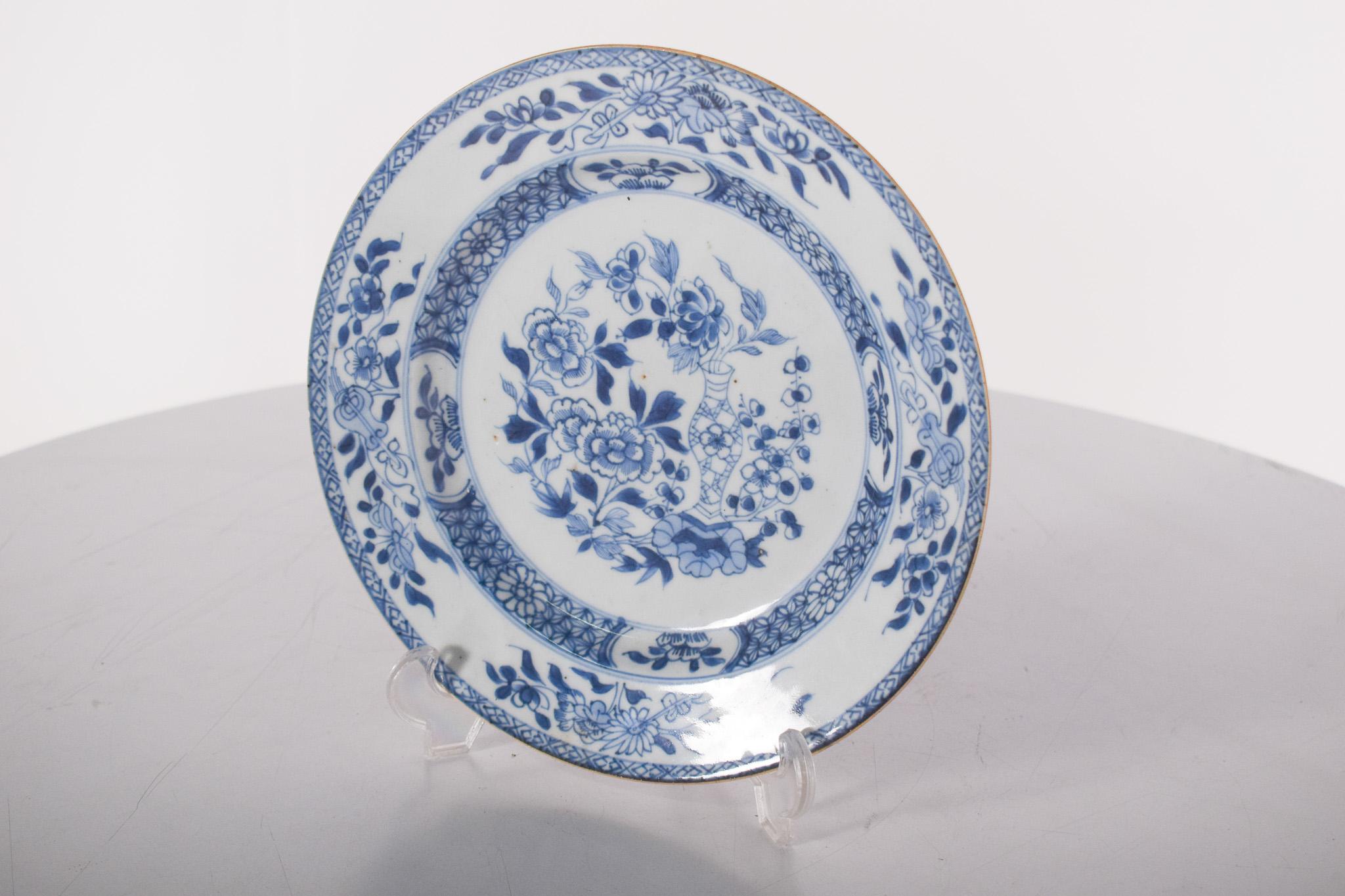 Piatto di porcellana dalla Cina per l'esportazione. Decorazione blu e bianca con motivi floreali. Dinastia Qing, periodo Qianlong (1736-1795).
Al centro, un vaso dal design delicato, da cui spuntano fiori e rami, circondato da una delicata