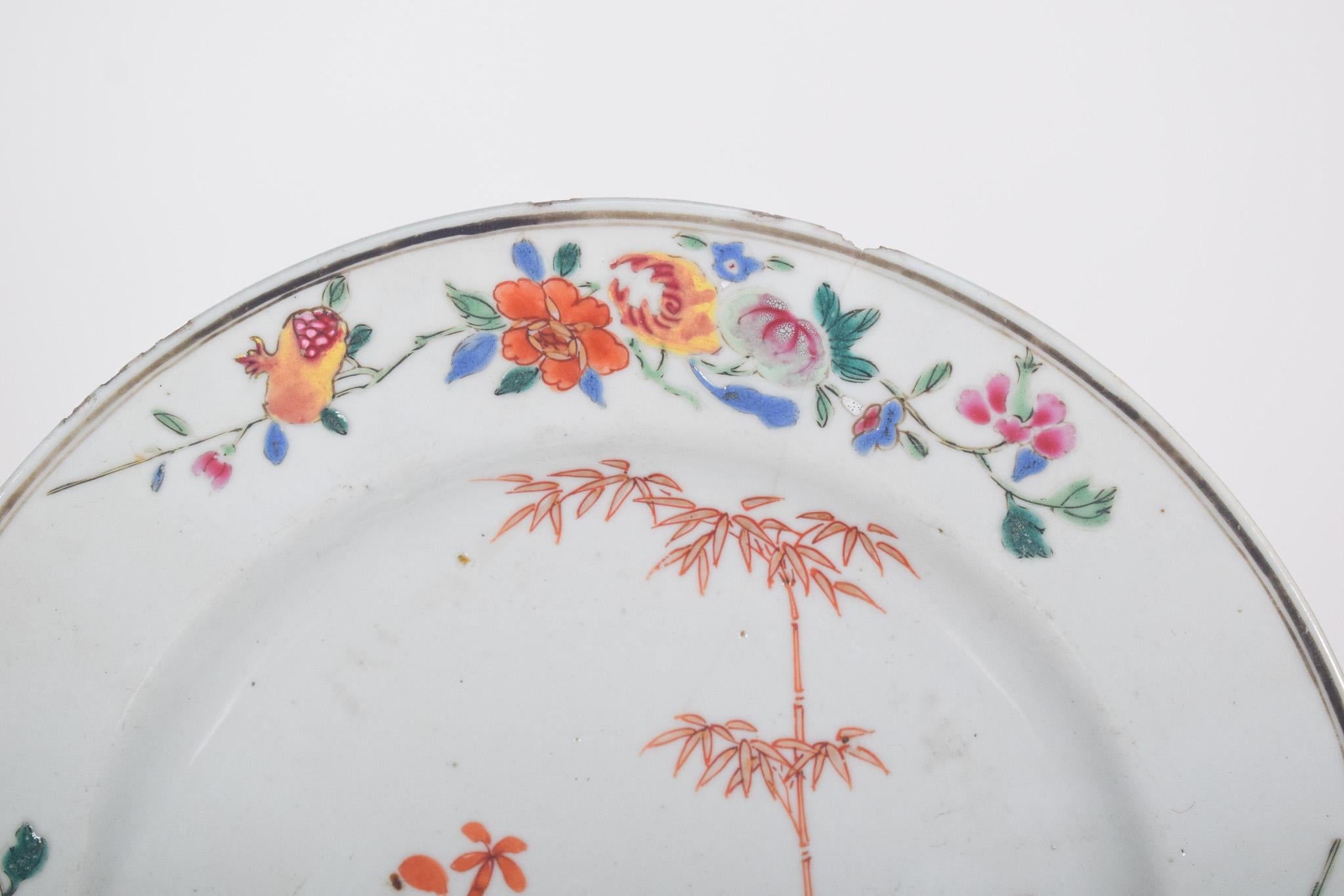 Chinese porcelain plate for export. Qing Dynasty, Qianlong period (1736-1795). Polychrome decoration, with an elegant floral pattern in vibrant shades of pink, orange and green. In the center, there is an exuberant composition with begonias, bamboo