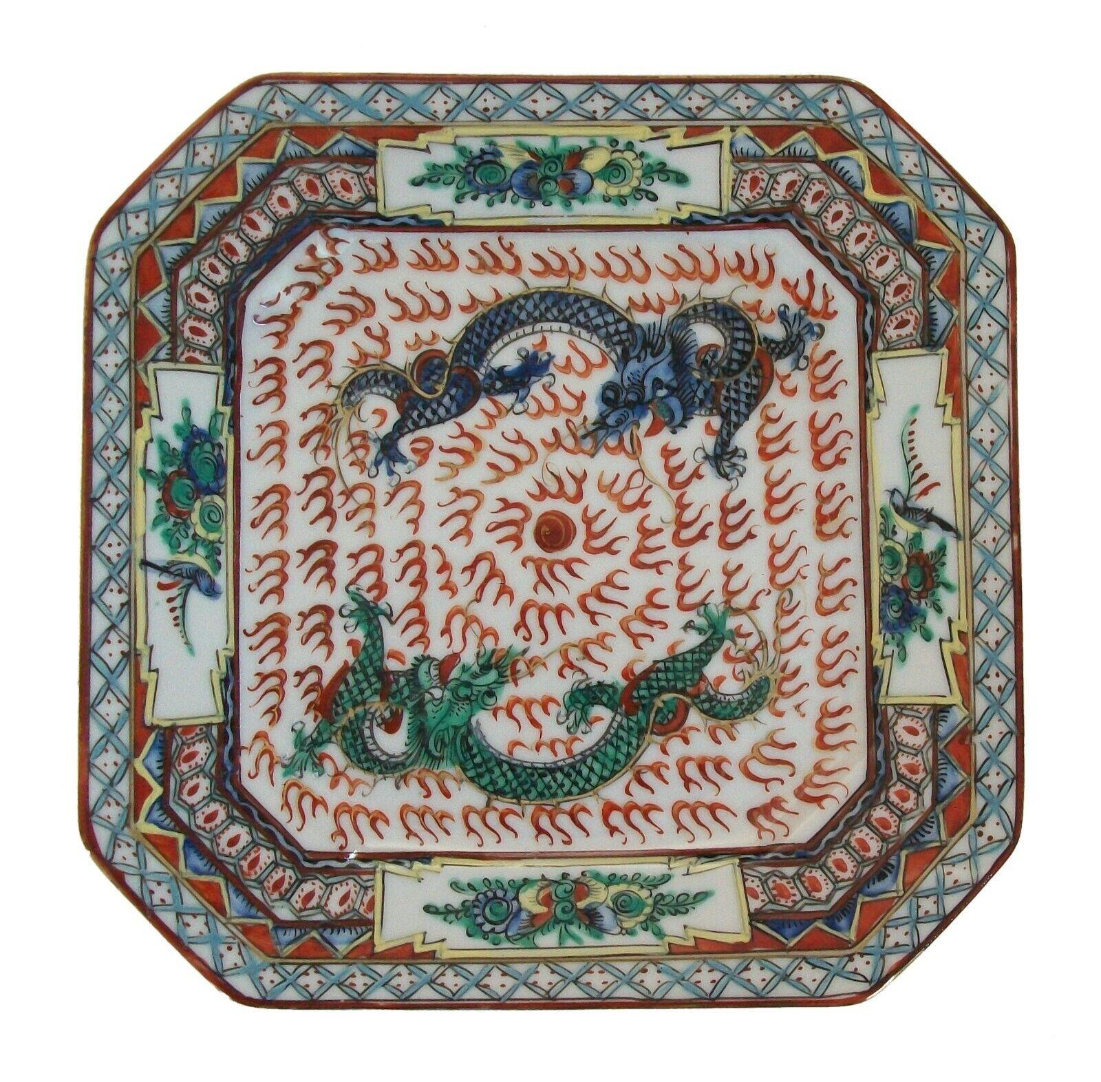 Assiette ancienne en porcelaine - peinte à la main de deux dragons poursuivant une perle enflammée - bordure florale et géométrique - coins inclinés - traces de dorure d'origine - signée d'une marque Qianlong à quatre caractères rouges au dos -