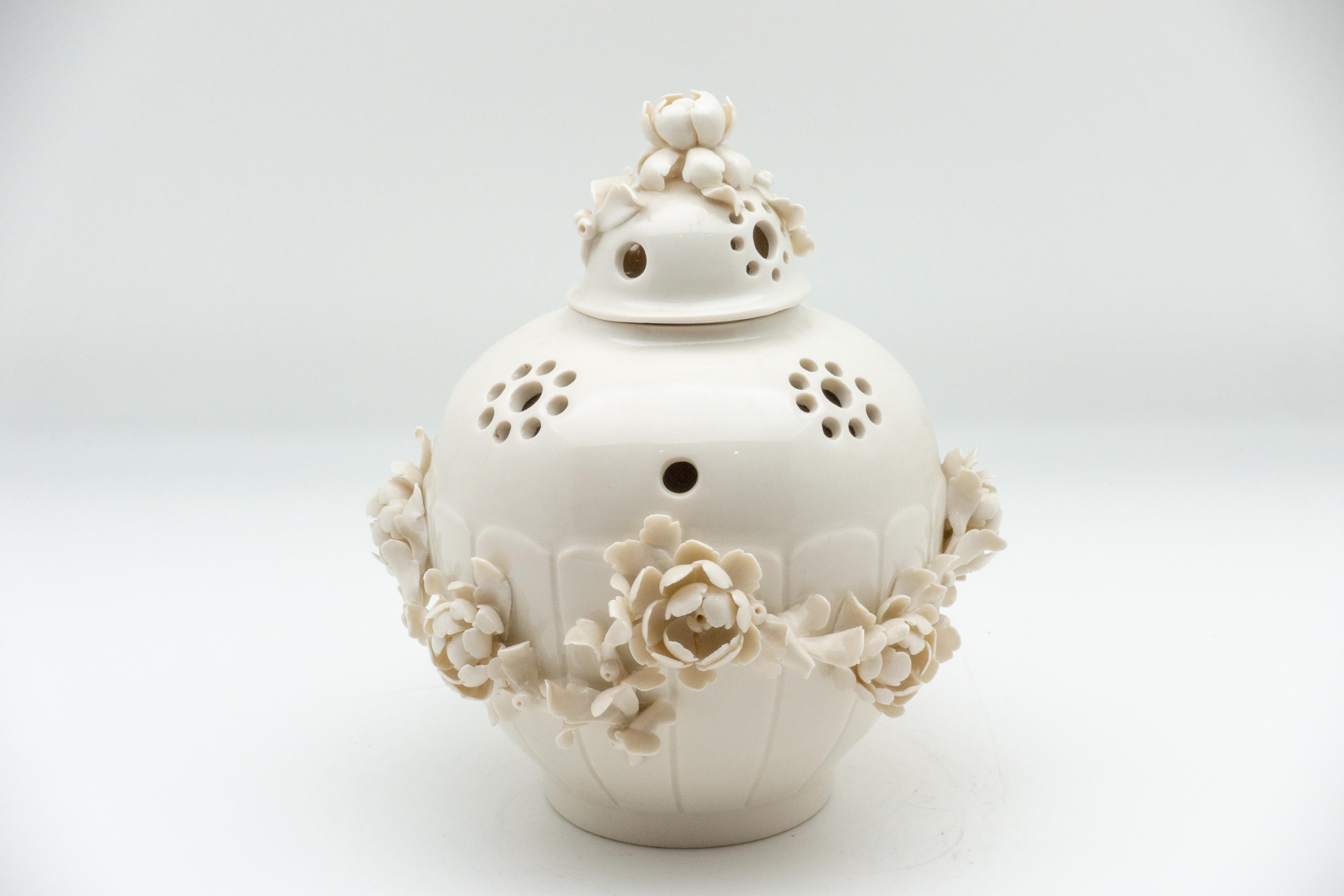 White porcelain pot-pourri vase in the style of the 18th century Saint-Cloud soft paste porcelain production, just outside of Paris, France. The vase has a pierced shoulder and the cover is domed, both applied with high relief garlands of flowers.