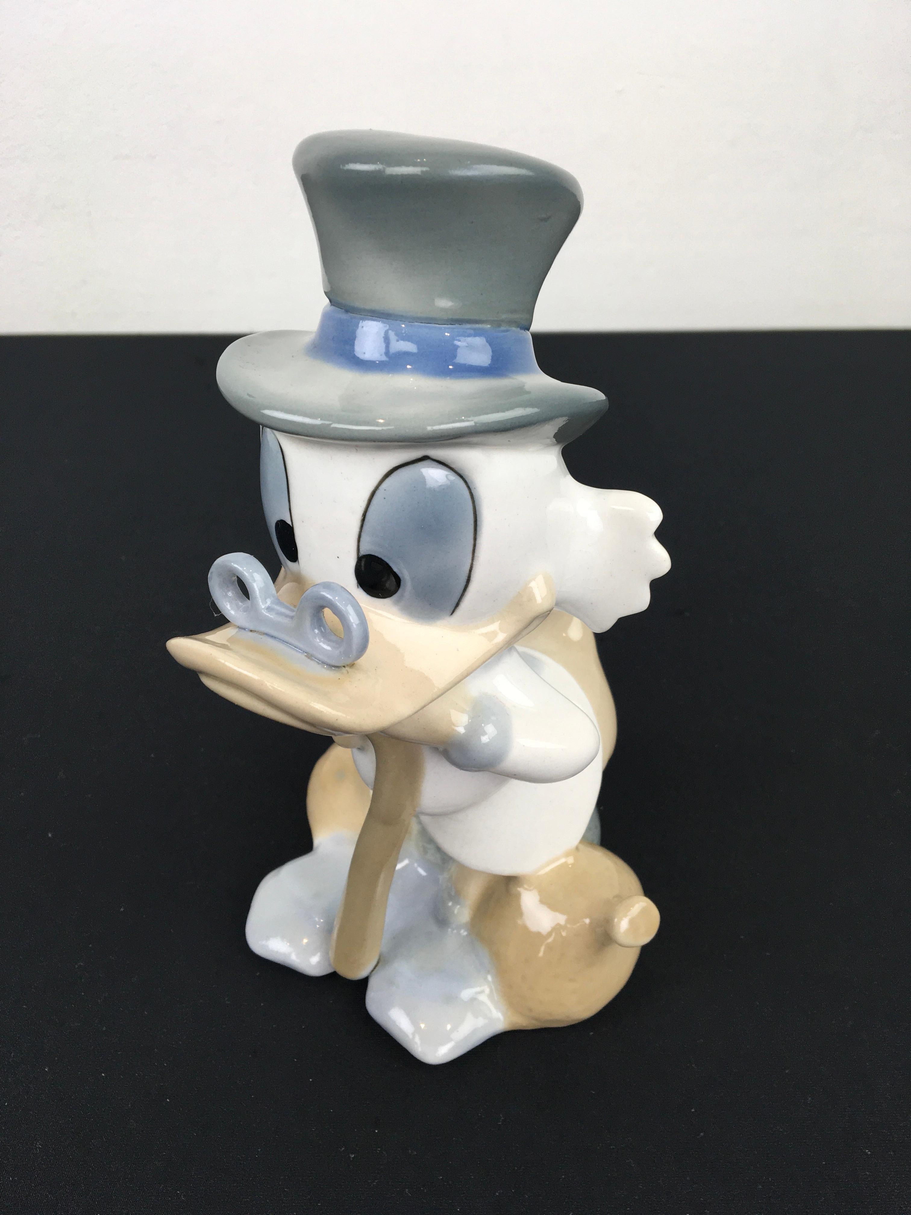 Porcelain Scrooge Mc Duck Figurine. 
A vintage glazed porcelain sculpture Made in Spain circa 1960 - 1980. 
Has stamps under. 
Disney character - Scrooge Mc Duck  - Dagobert Duck - Donald Duck. 
In beautiful colors blue - beige and white with the