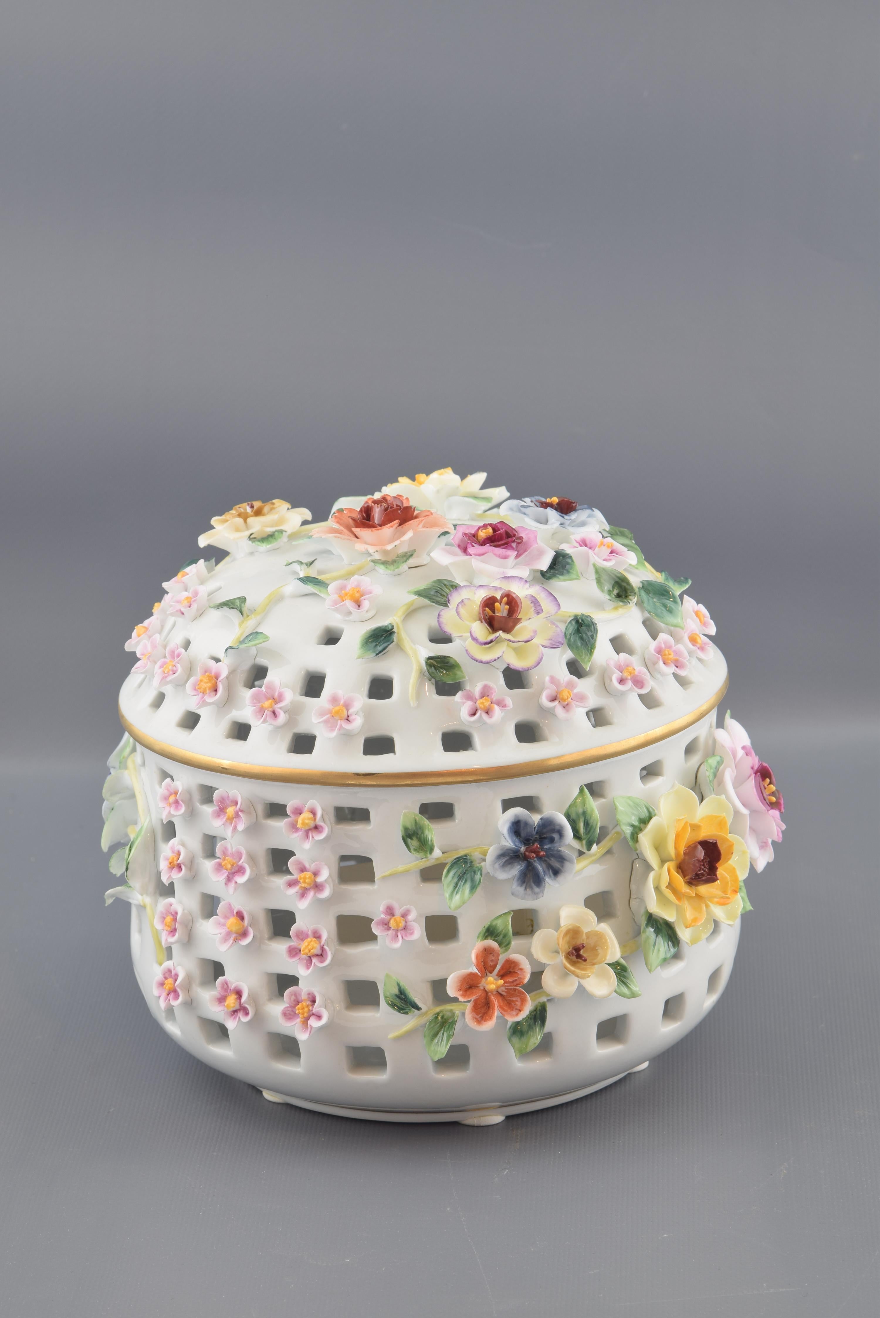 The bonnet with lid is set on almost all its surface, and is adorned with roses, stems and small flowers of different colors on the openwork surface. This type of porcelain was very popular in Europe since the 18th century, with models similar to