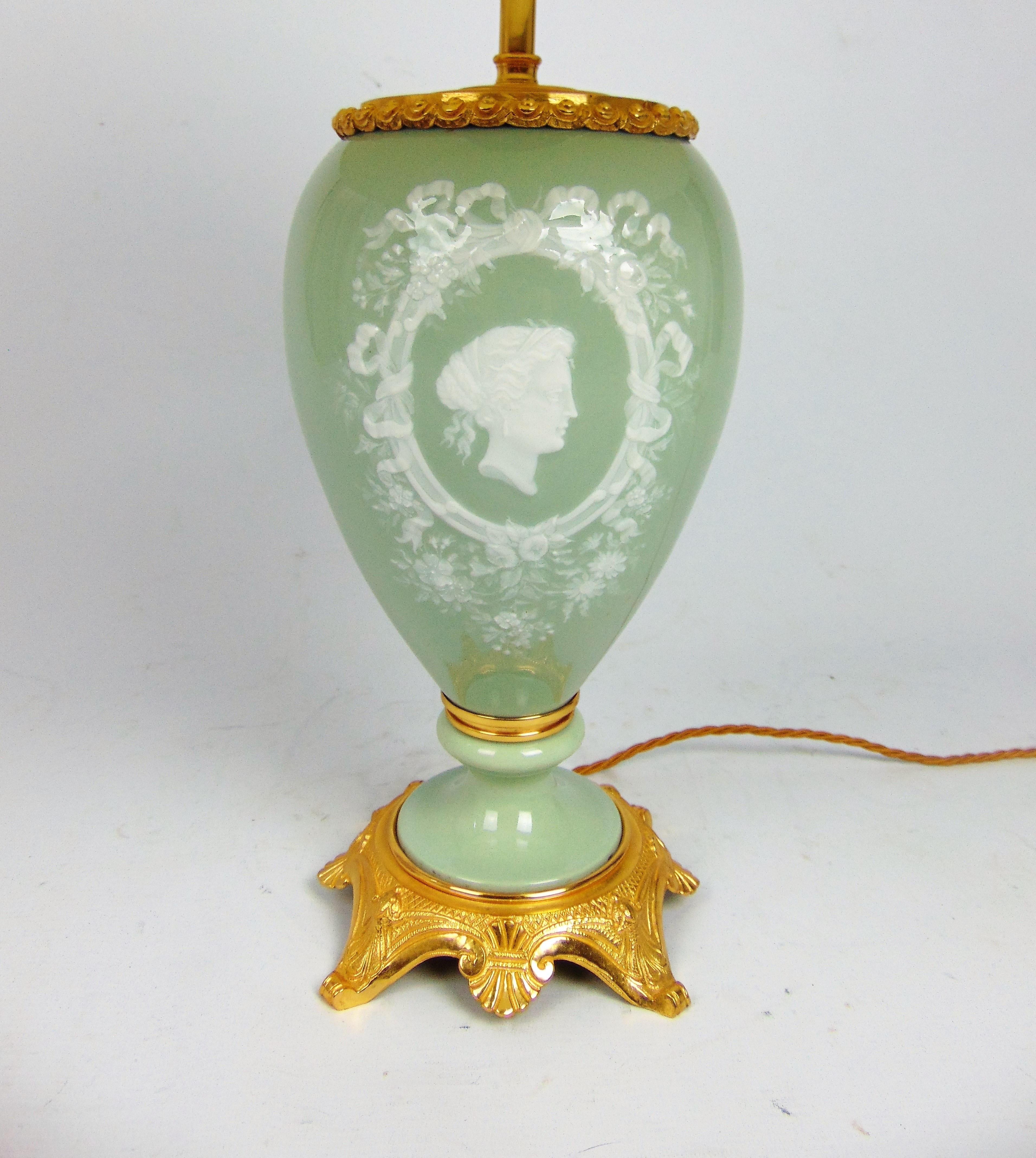 A fine French Porcelain lamp with Celedon ground and Pate sur pate decoration of a classical maidens profile cameo surrounded with ribbon tied floral detail to the front and floral spray to the reverse on quality gilt bronze base.
Re-wired and Pat