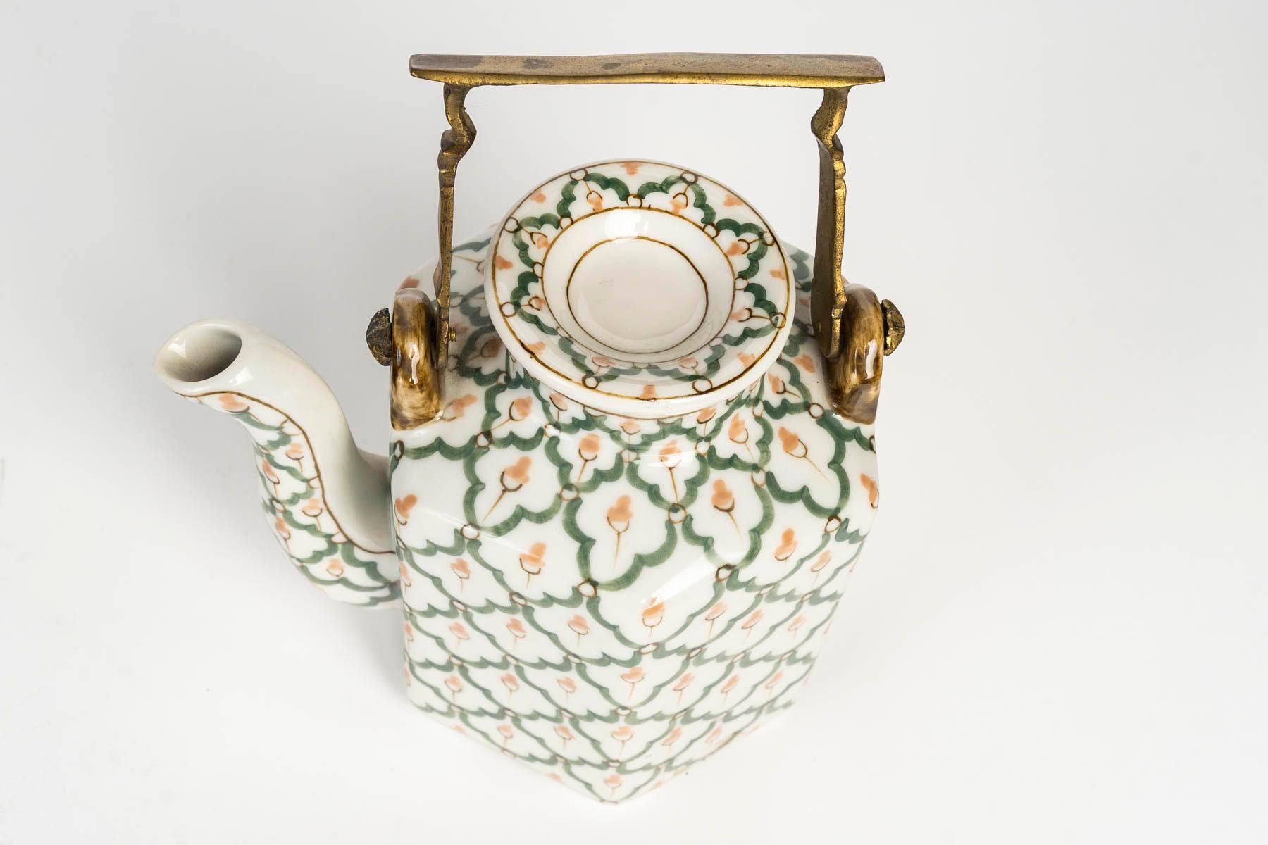 Porcelain teapot, bronze handle, 20th century.

A 20th century porcelain teapot with a bronze handle.
H: 18cm, W: 14.5cm, D: 10cm