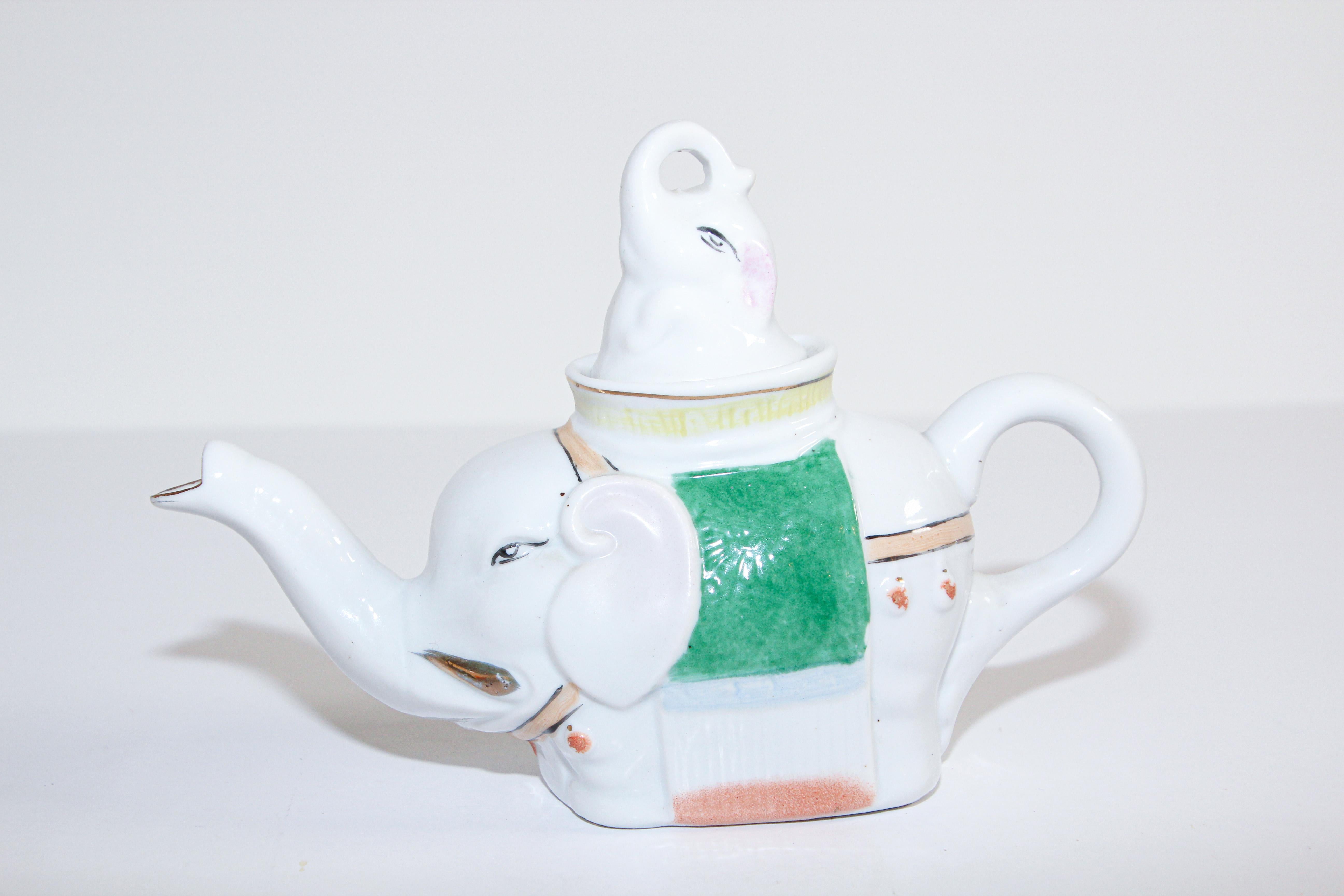 Porcelain teapot in the form of an elephant carrying a baby elephant.
Vintage elephant tea pot made in Japan, beautiful coloring flower work is done on porcelain,
This wonderful oriental ceramic tea pot is modeled as a standing elephant carrying a
