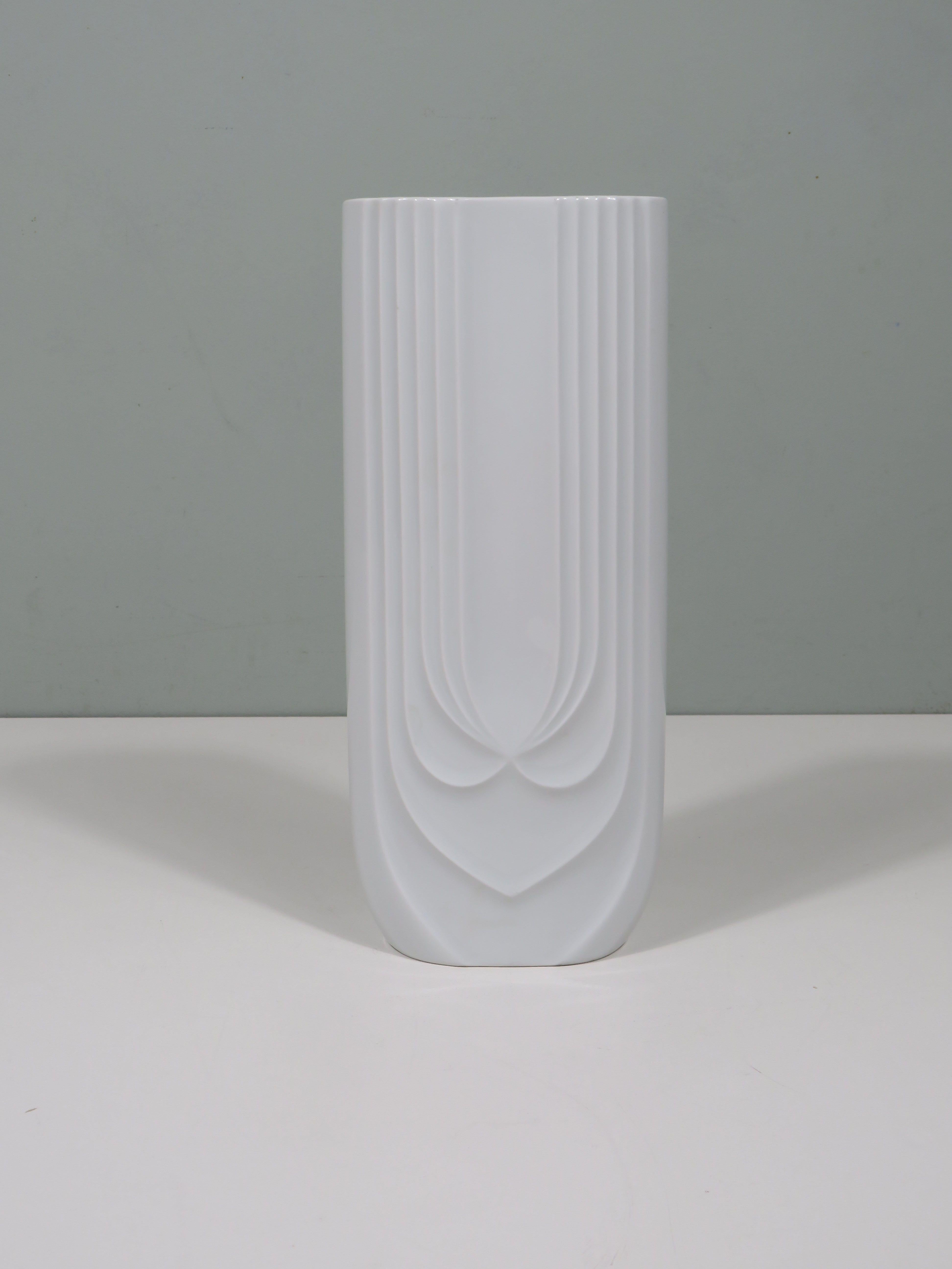 Diese Vase aus weißem, glänzendem Porzellan von Hutschenreuther verbindet Handwerkskunst mit modernem Design. Die glänzend glasierte Oberfläche und die anmutigen Reliefdetails machen sie zu einer vielseitigen und zeitlosen Ergänzung für jedes