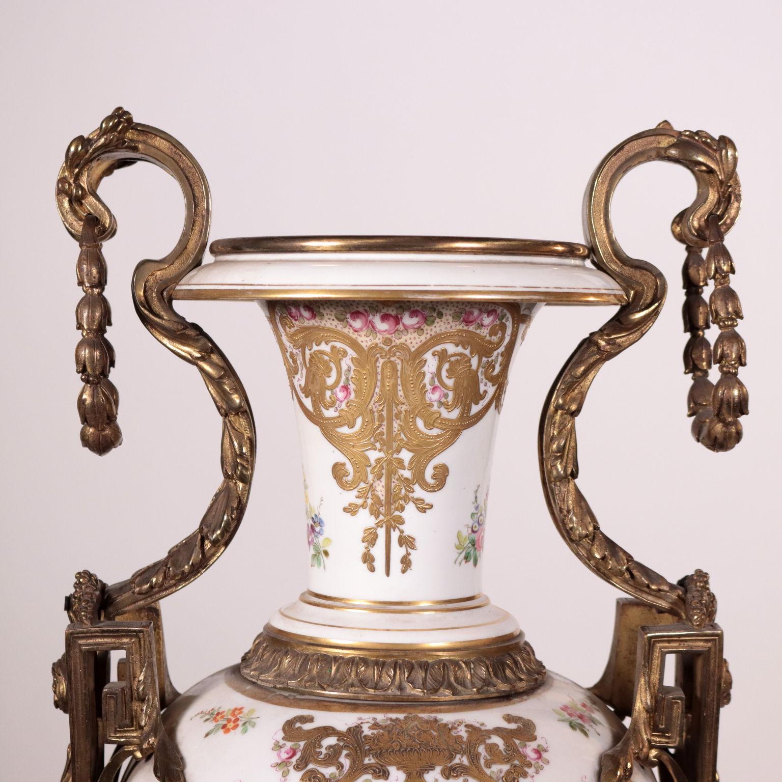 Large porcelain and gilded bronze vase. The vase is supported by a square gilded bronze base, chiselled with vegetal motifs decorations. A spilled porcelain cup and a brass cap support the body of the vase, finely decorated with paintings inside the