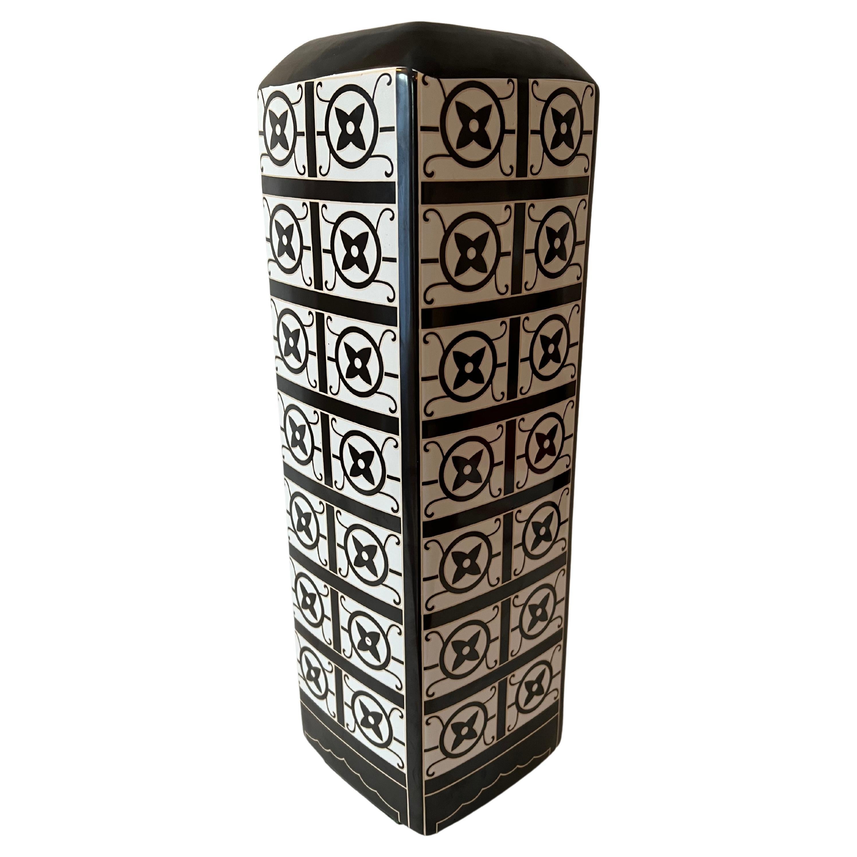 A porcelain vase with black / white and gold designs of the Louis Vuitton Logo with Flower pattern. With a size and width that work well for height on a console, desk or cocktail table. 

The height with a bouquet of flowers makes a very nice