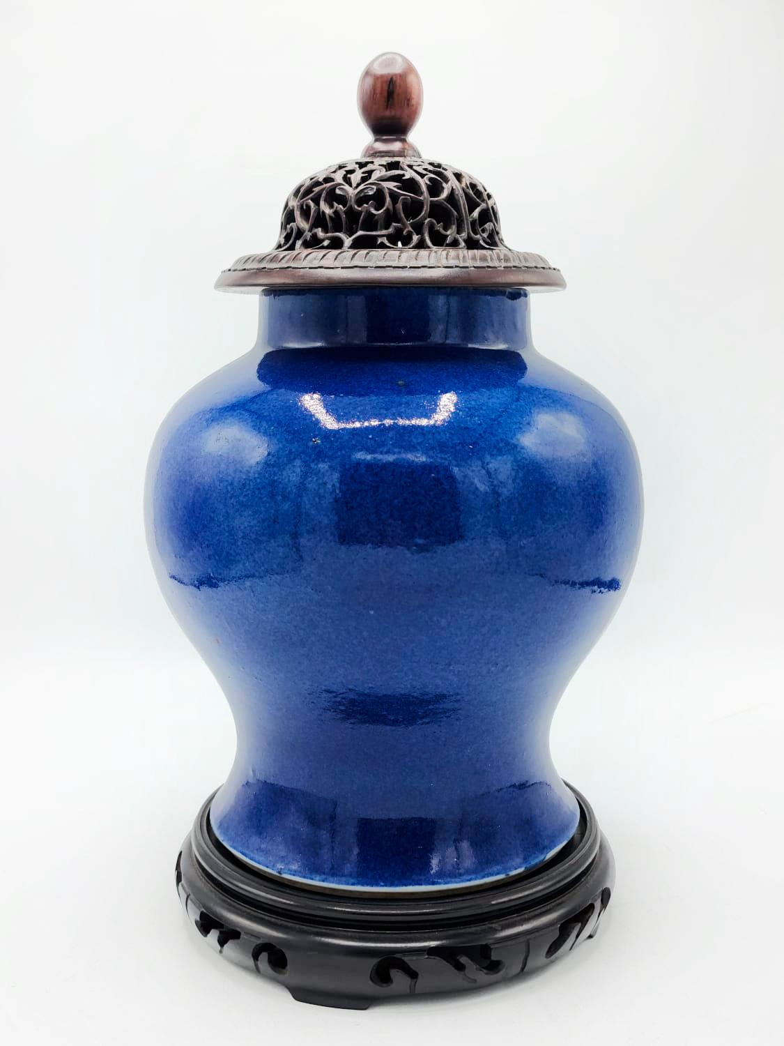 Porcelain vase with carved wooden lid, 19th century Kangxi period

Blue porcelain vase, with carved wood base and lid. The Cover in specific has a quite elaborate design due to its fluid lines and finely crafted details.
Belonging to the Quing