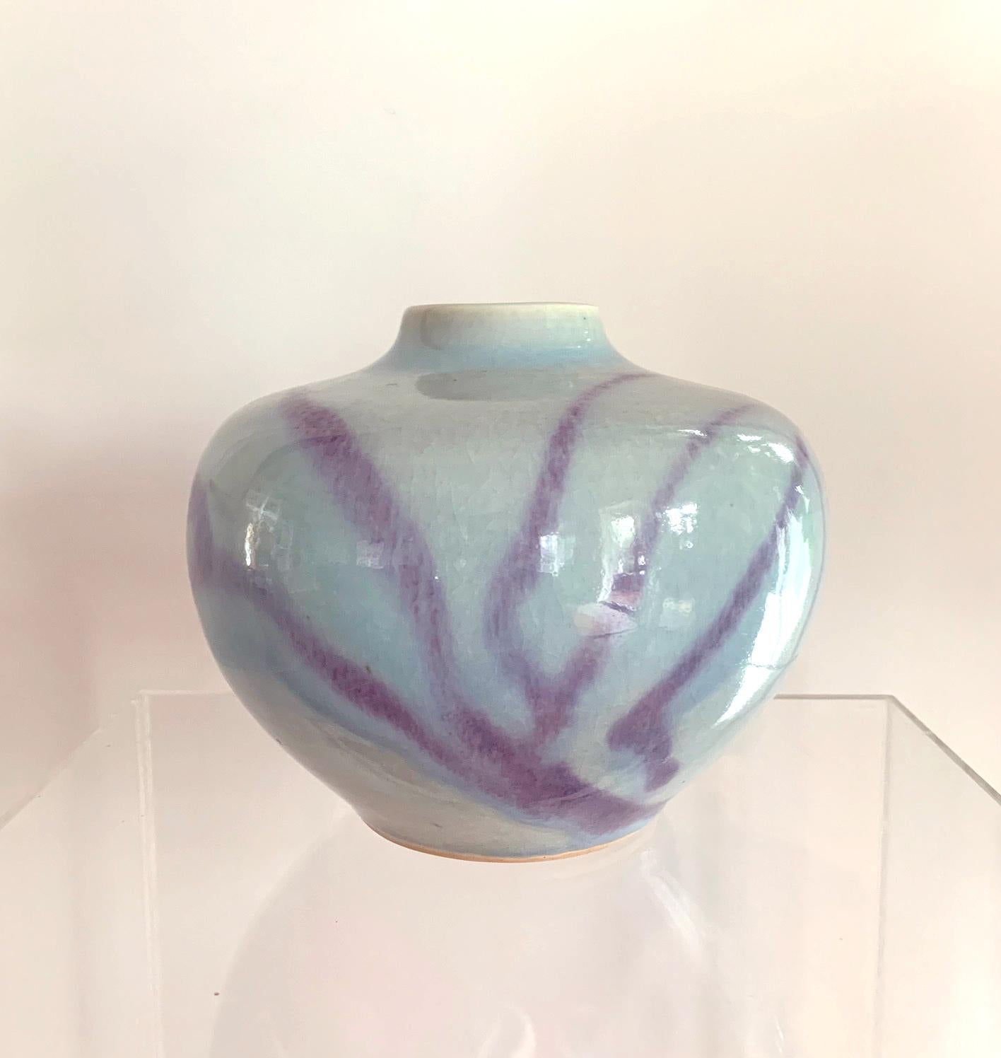 A Bulbous form porcelain vase of a slight lavender tinted celadon glazed with abstract strokes and splashes of a copper red glaze, made by Brother Thomas Bezanson (1929-2007). With its perfect form, the high glossy surface with fine crackles and the