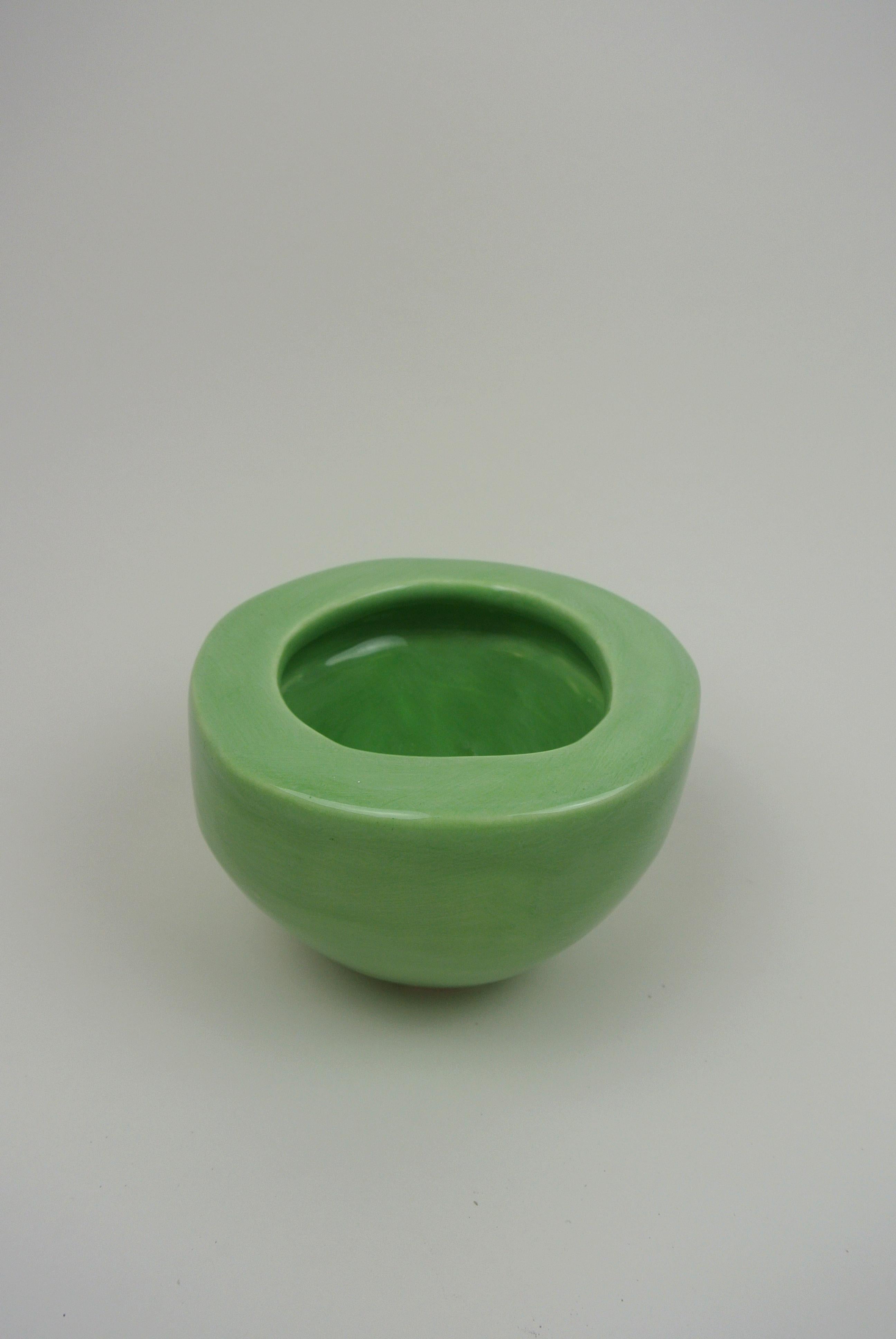 Asymmetric white porcelain vessel with wide rim. Carved by hand and glazed with green glossy glaze. Holds water.
