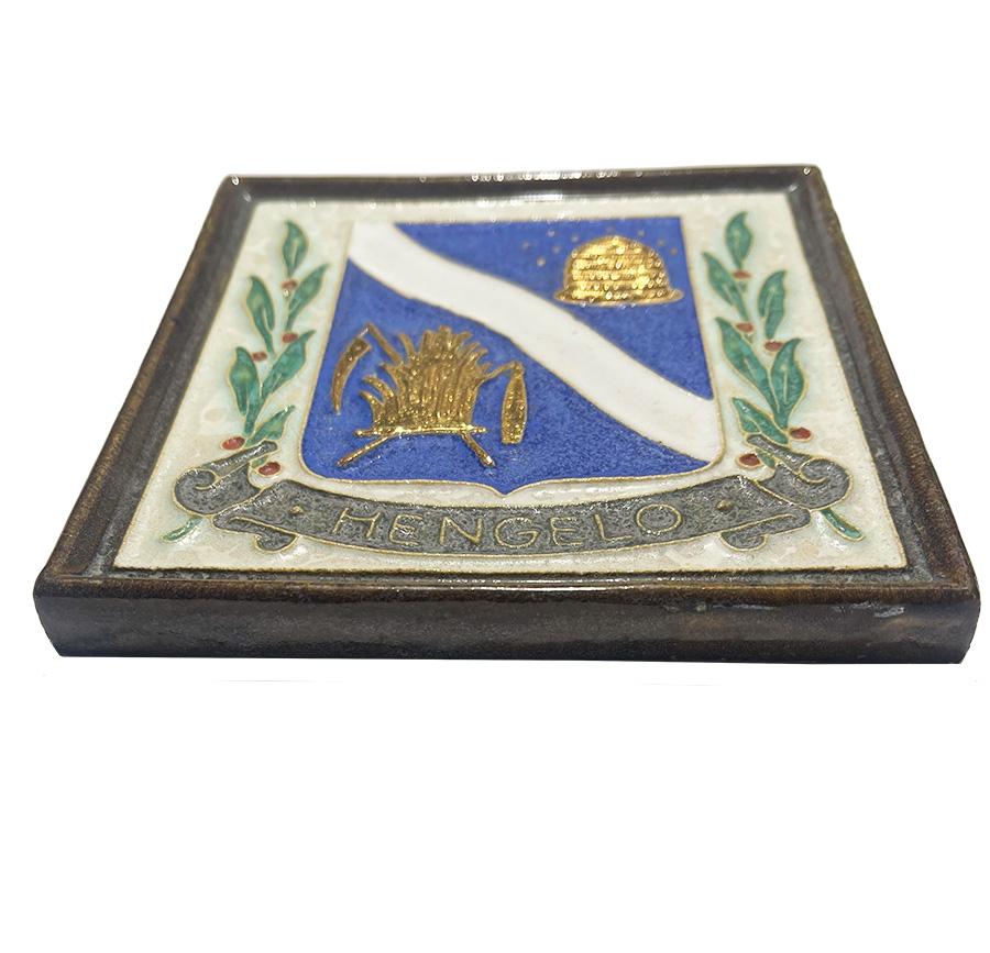 Porceleyne Fles Delft cloisonné tile with the coat of arms of Hengelo

A decorative earthenware tile with cloisonné in relief
Hengelo is a City in the East of The Netherlands
The cloisonné tiles of the Porceleyne Fles are made during 1907-1977 in
