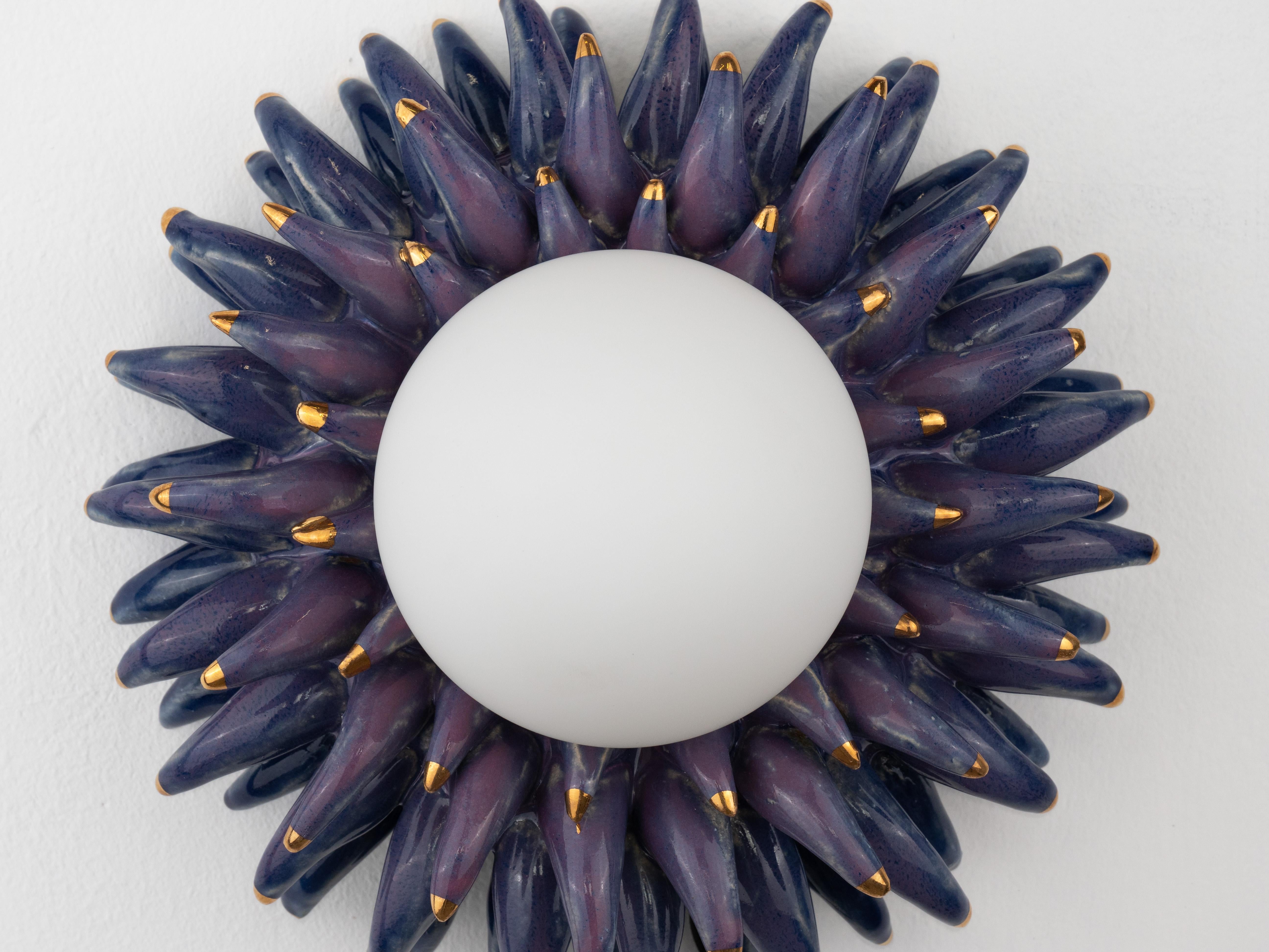 Inspired by our Devin monster series, this handmade ceramic wall light has a bold, spiky design with pink and deep purple tones and 24k gold tips, giving it a striking, modern look. The mix of rich colours and sharp details makes it a real statement