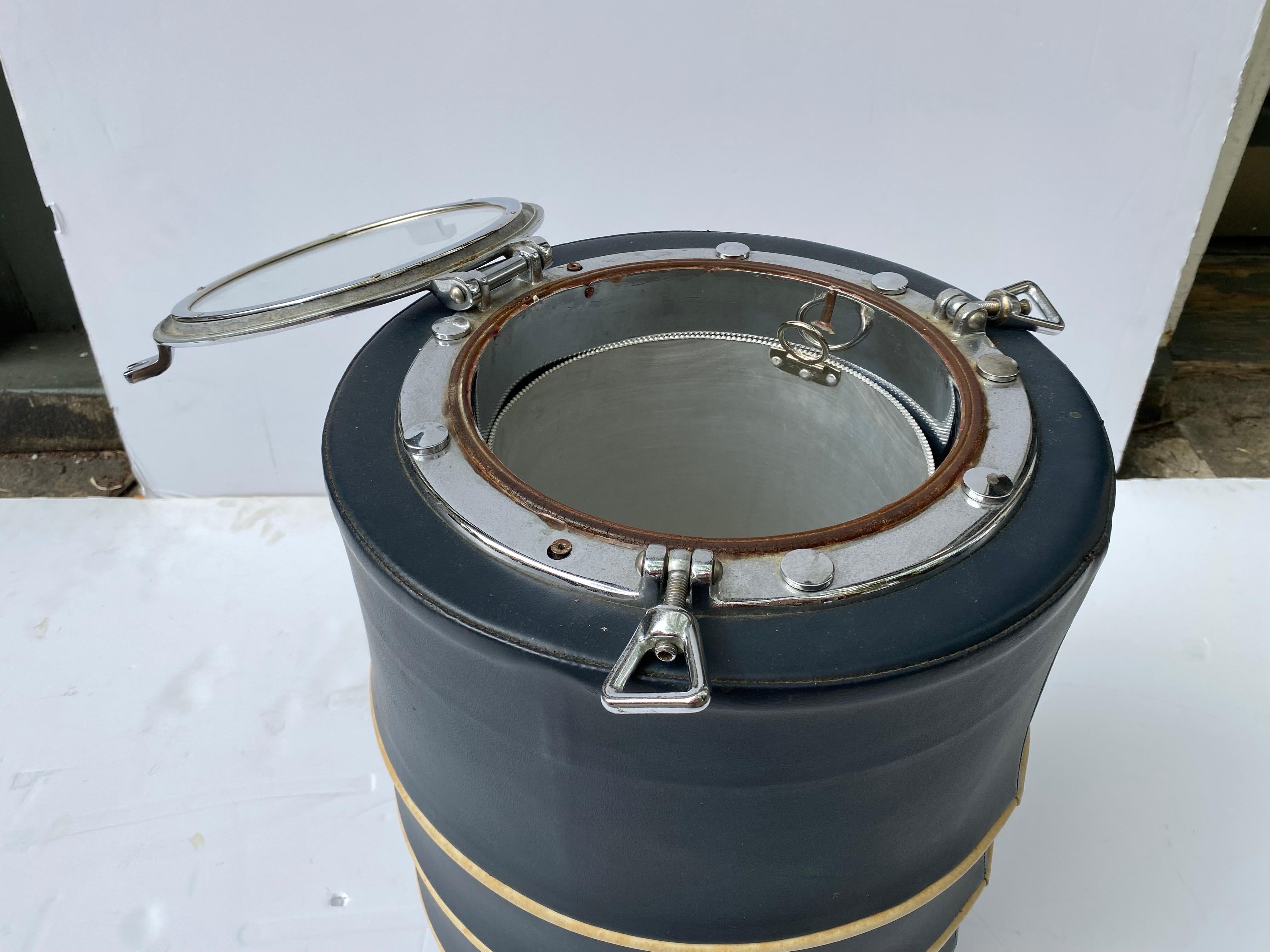 Port Hole Topped Ice Bucket Designed and Built by Michael Smith and Depression Modern. Clever design with a interior removable liner to hold ice. Covered in a dark blue vinyl with tan piping. This one dates to the early 1990's. overall in good shape