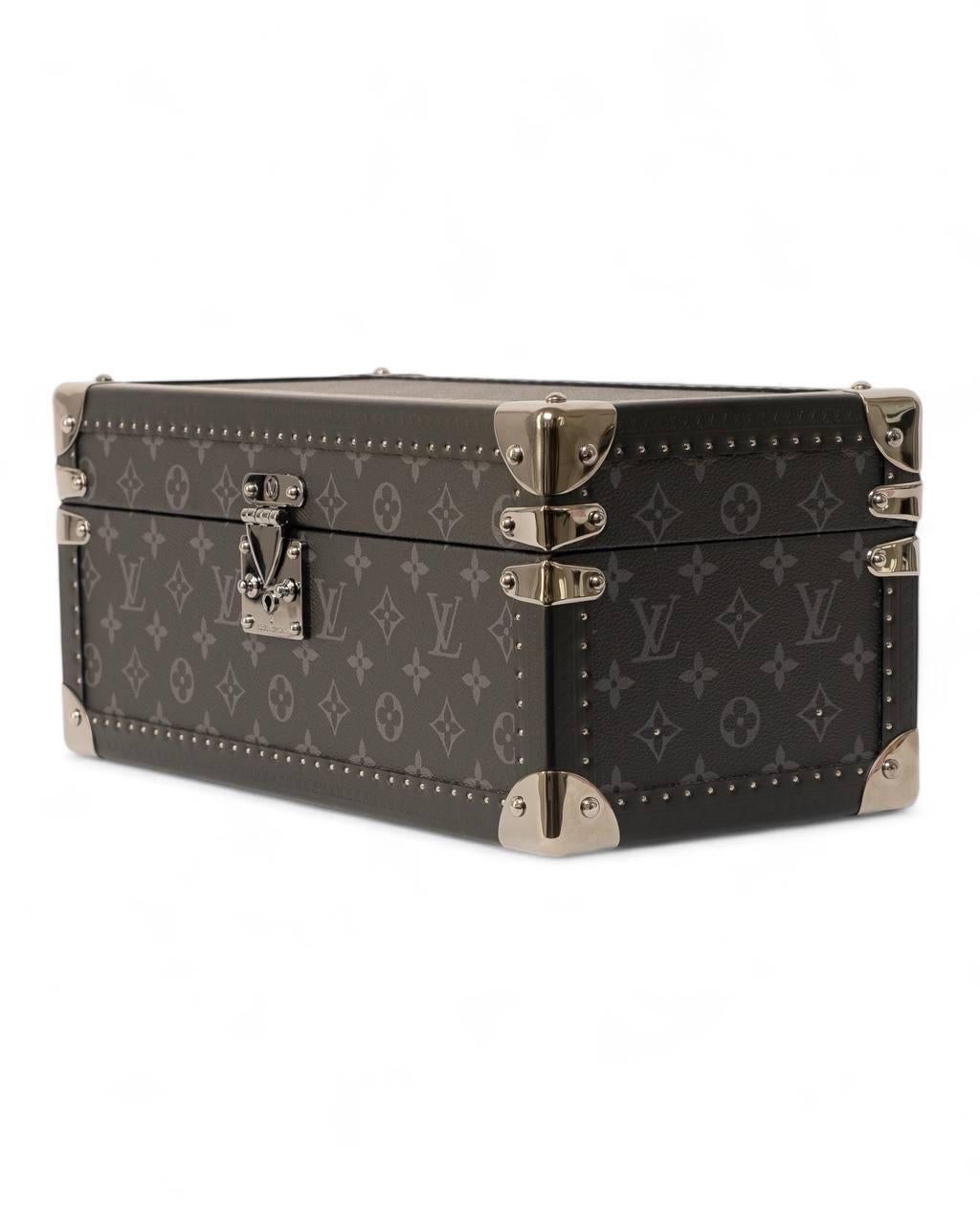Porta Orologi firmato Louis Vuitton, realizzato in tela nella classica fantasia monogram Eclipse nera con rifiniture in pelle e hardware dorati. Dotato di una chiusura frontale ad incastro, internamente rivestito in tessuto scamosciato rosso,