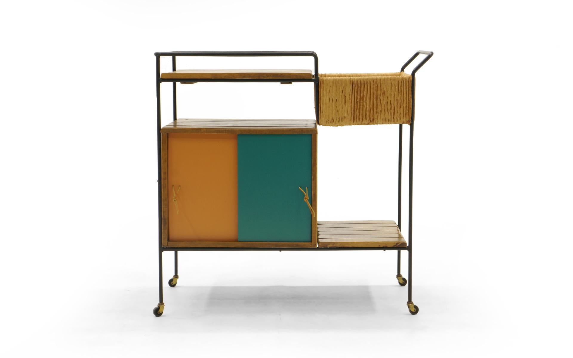 Bar Trolley by Arthur Umanoff. The sliding Masonite doors also have a white and blue side. This is a Fine example in original condition with restored door panels to give is a crisp clean appearance. Also new leather string pulls.