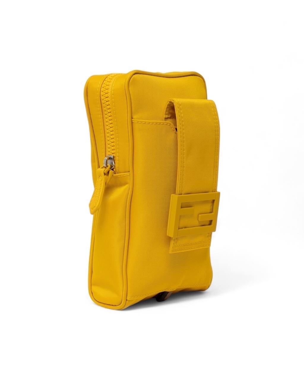 Portacellulare firmato Fendi, realizzato in nylon nella colorazione gialla con hardware argentati. Dotato di una chiusura superiore a zip, internamente rivestito in tessuto nero, capiente per l’essenziale. Munito di ua tracolla rimovibile e