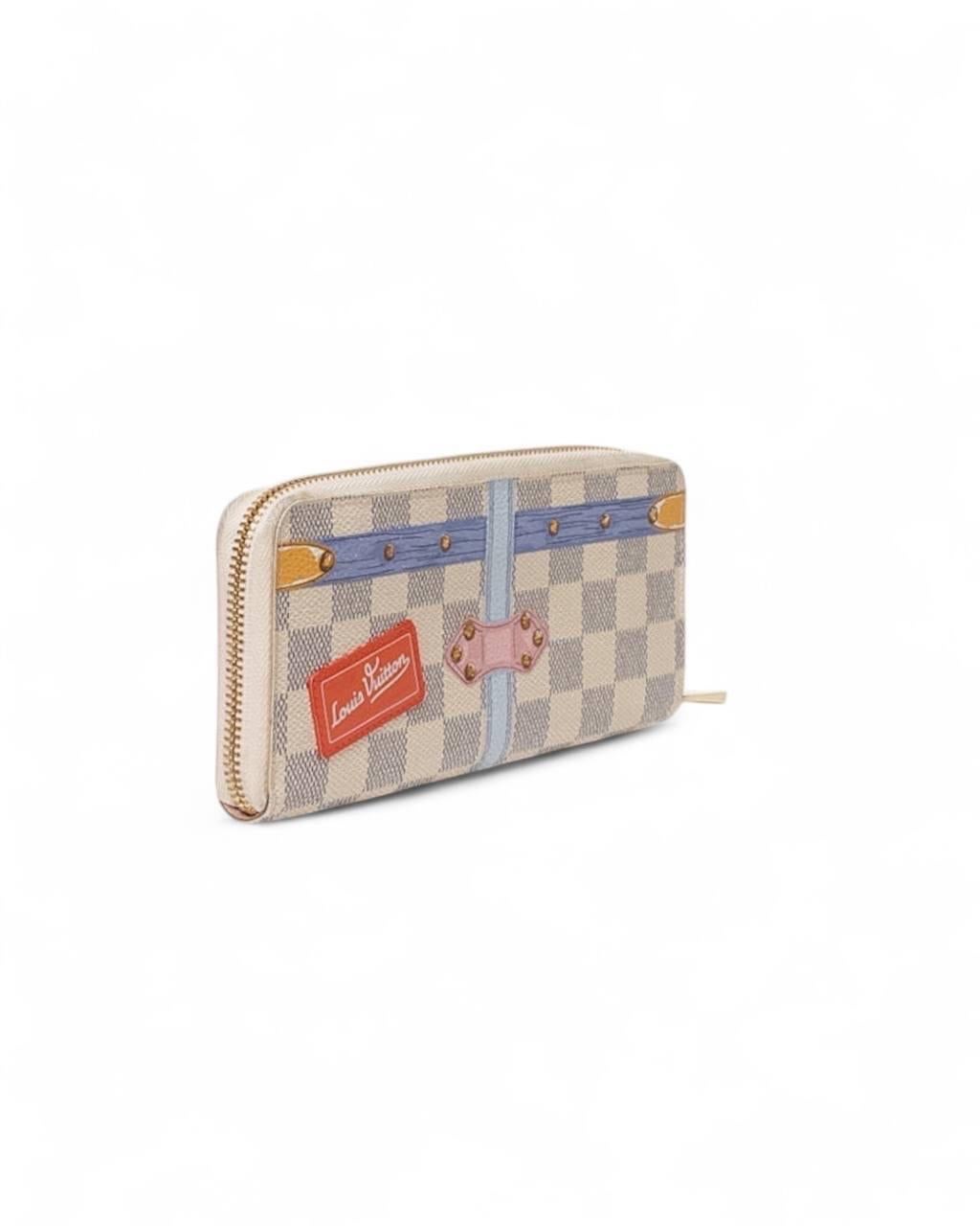 Portafoglio firmato Louis Vuitton, in edizione limitata Summer Trunks, realizzato in tela beige a fondo damier con hardware dorati. Dotato di una chiusura a zip, internamente rivestito in pelle rosa con molteplici scompartimenti con e senza zip.
