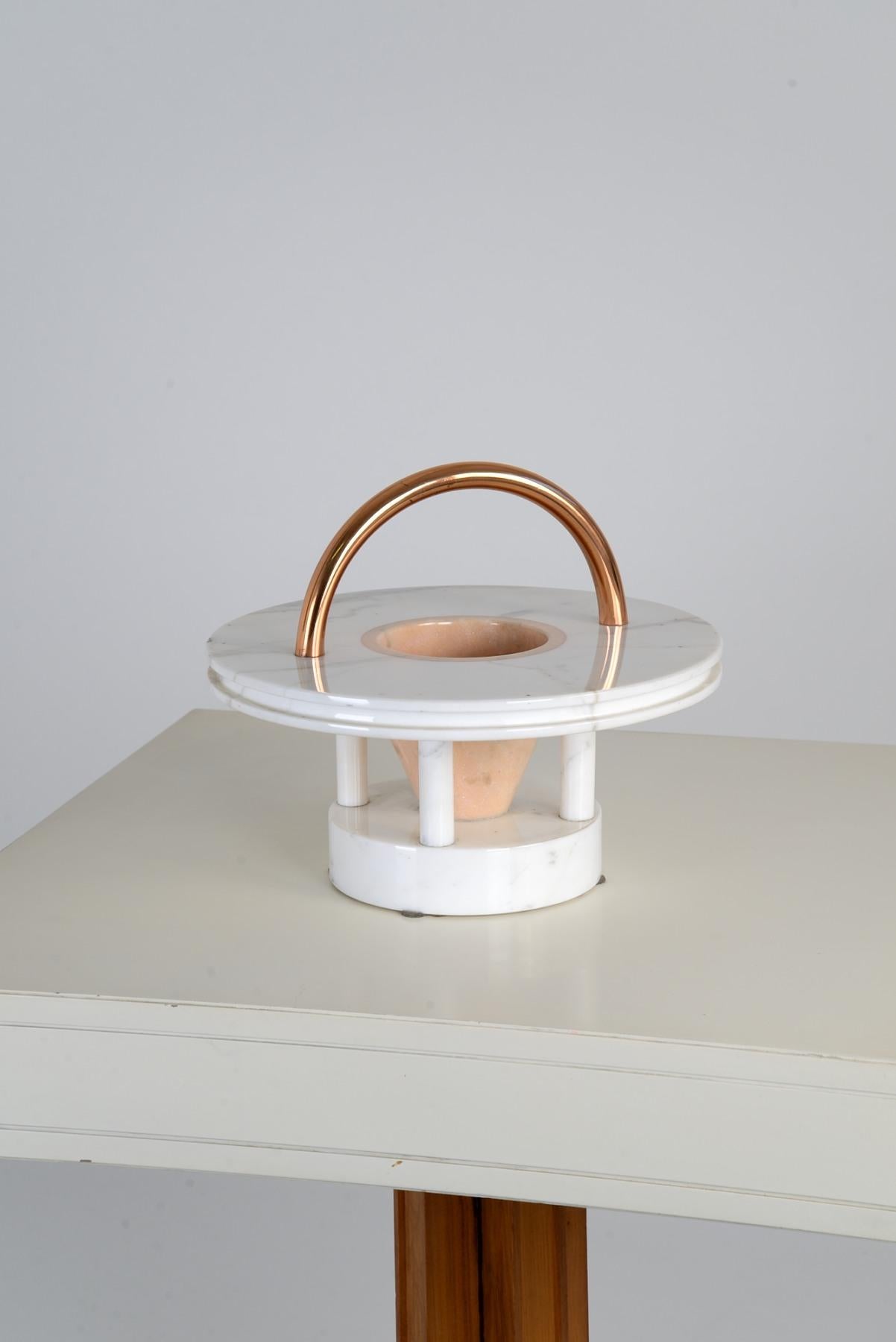 Iconic fruit bowl model Gaya, designed by Ettore Sottsass in 1983 for Up&Up (now part of UpGroup), a famous Tuscan marble manufacturer.
The sculpture combines a Carrara marble base with a copper handle that accentuates its totemic and sculptural