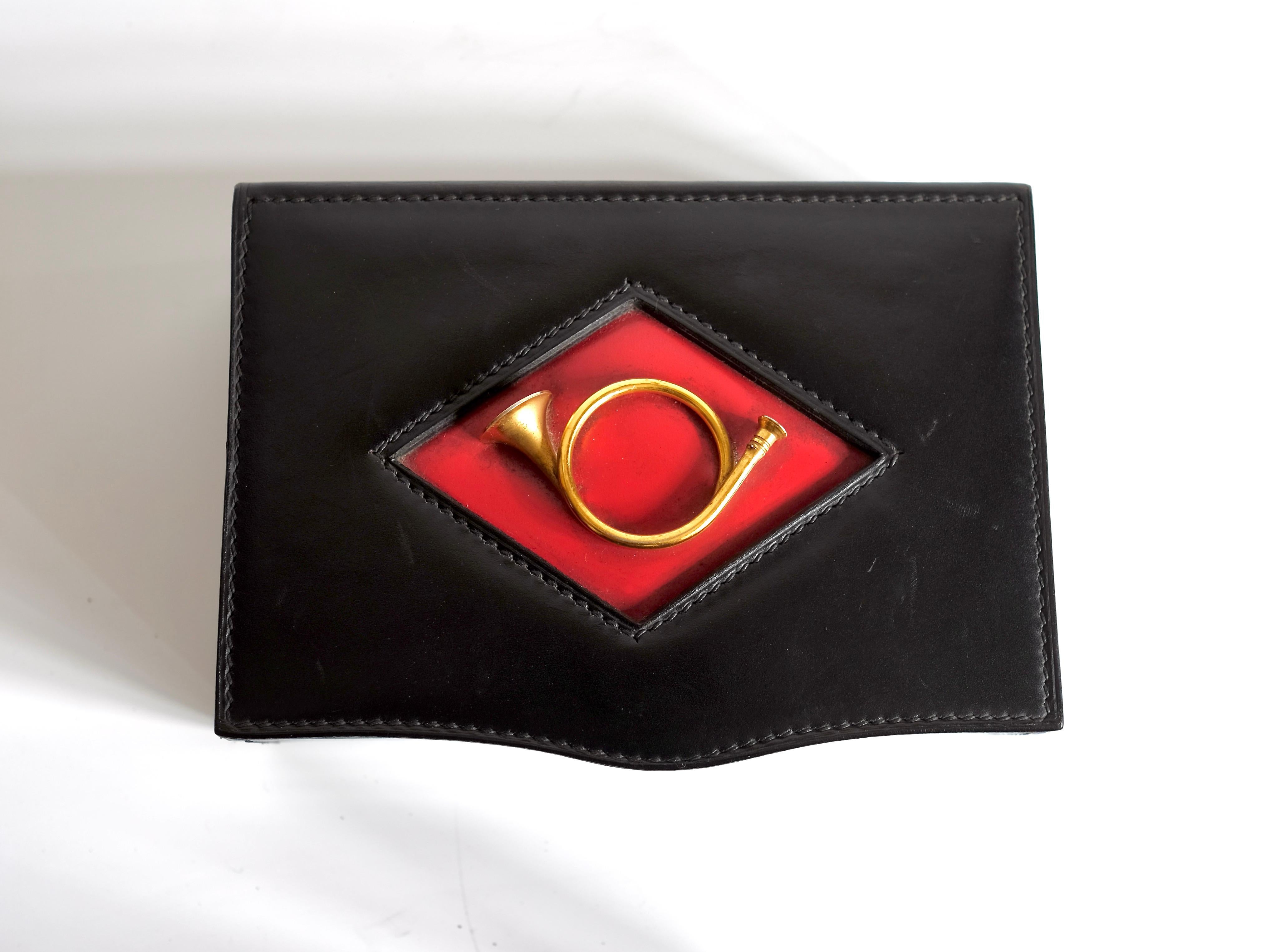 Raro portagioie in pelle GUCCI collezione anni 1960/70, la decorazione centrale a losanga con elegante tromba da caccia in bronzo dorato e l'interno in colore rosso lacca conferisce a questo oggetto particolare fascino. È lo stile e la qualità