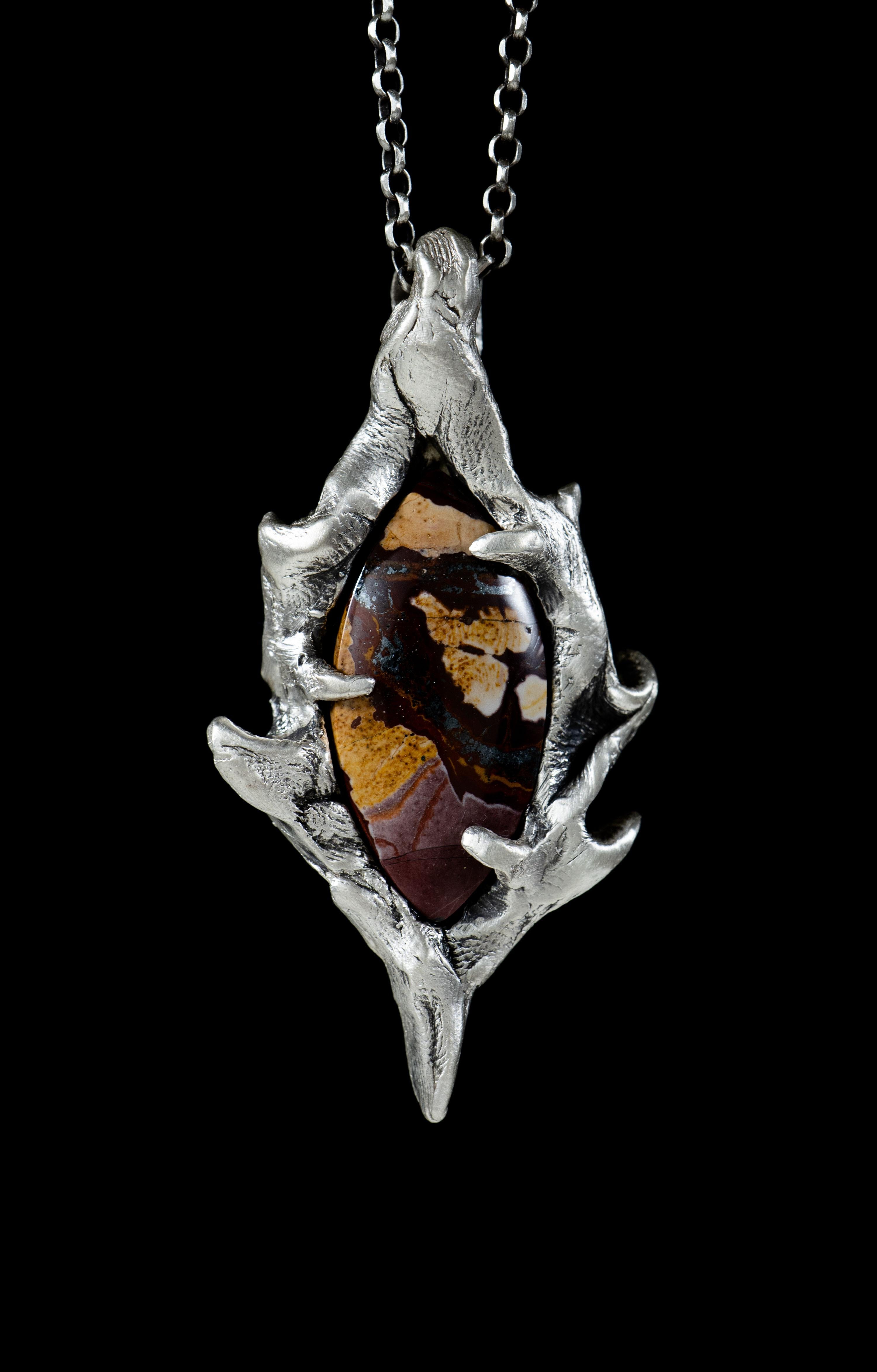 Portal is a one-of-a-kind pendant by Ken Fury that is hand-carved and cast in sterling silver and features a natural Red & Green Blanket Jasper from Peru. The pendant has a satin finish. 

Size of piece: 64mm x 34mm

Hand-signed

Includes a 24-inch
