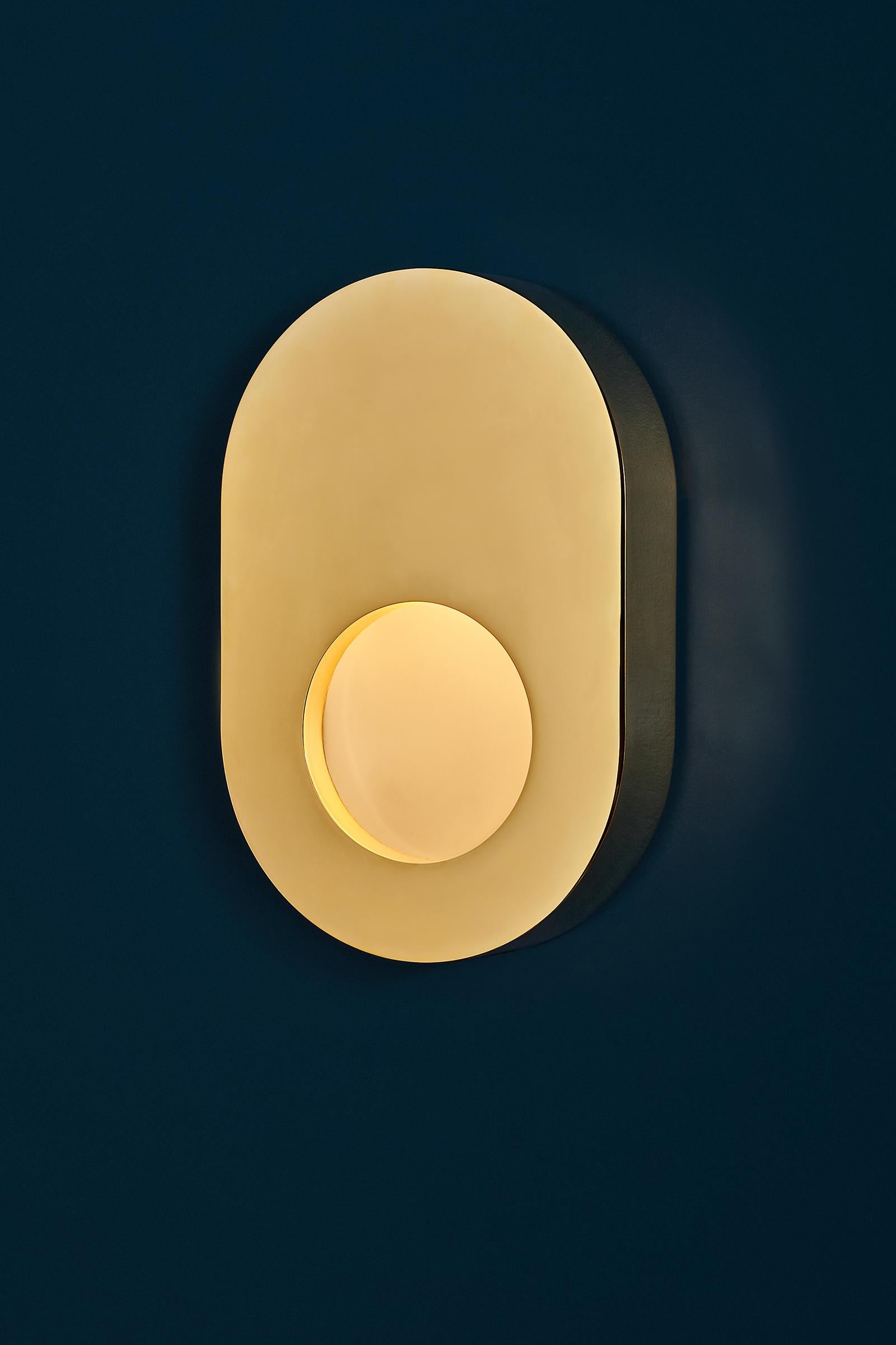 The Portal Sconce features a hand-finished brass body and an inset light diffused through textured glass, creating a warm, delicate glow. 

This sconce is made from brass and polished by hand. Also available in an antique brass finish or custom