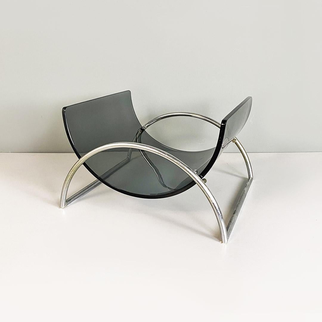 Italian Lira magazine rack by Pierangelo Gallotti for Gallotti and Radice, 1980s.
Lira model magazine rack with curved steel rod structure and curved smoked glass support surface inserted between four bolts that hold it in place, also thanks to its