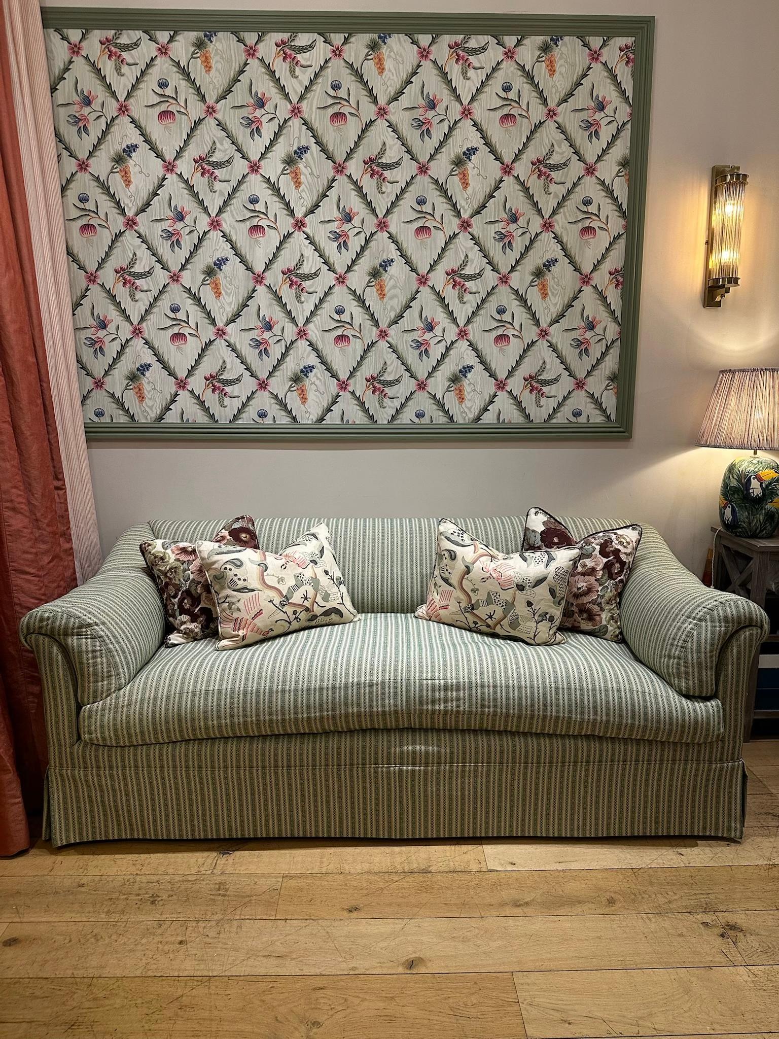 This sofa is a contemporary re-edition of the Howard & Sons “Portarlington” model, a form closely associated with late-19th-century English domestic design. The proportions are faithful to the original: a softly sloped back, low scroll arms and a